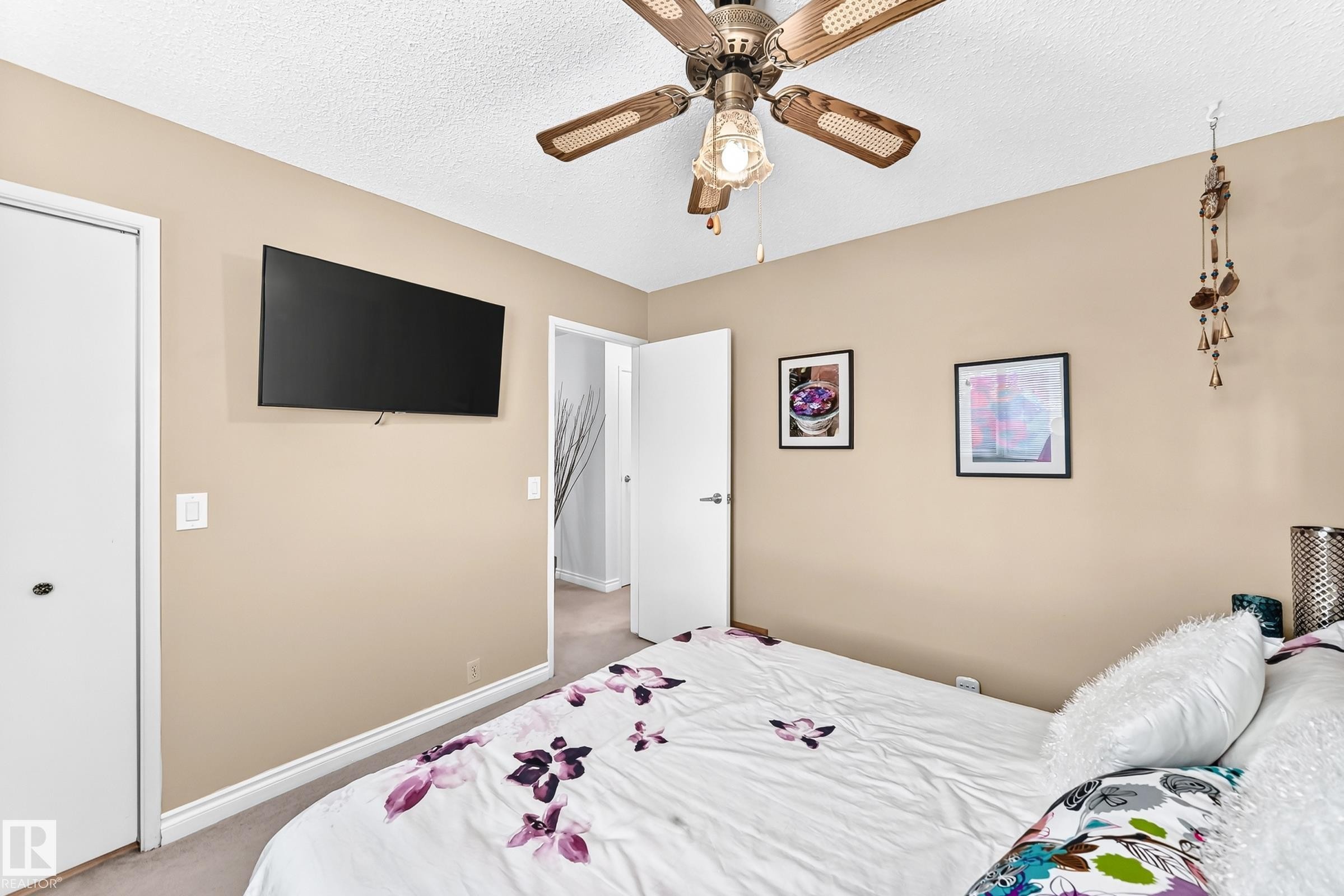 Ceiling fan with light fixture, wall-mounted television, neutral wall color, white trim, and white doors - 5620 93A Avenue Nw, Edmonton, AB