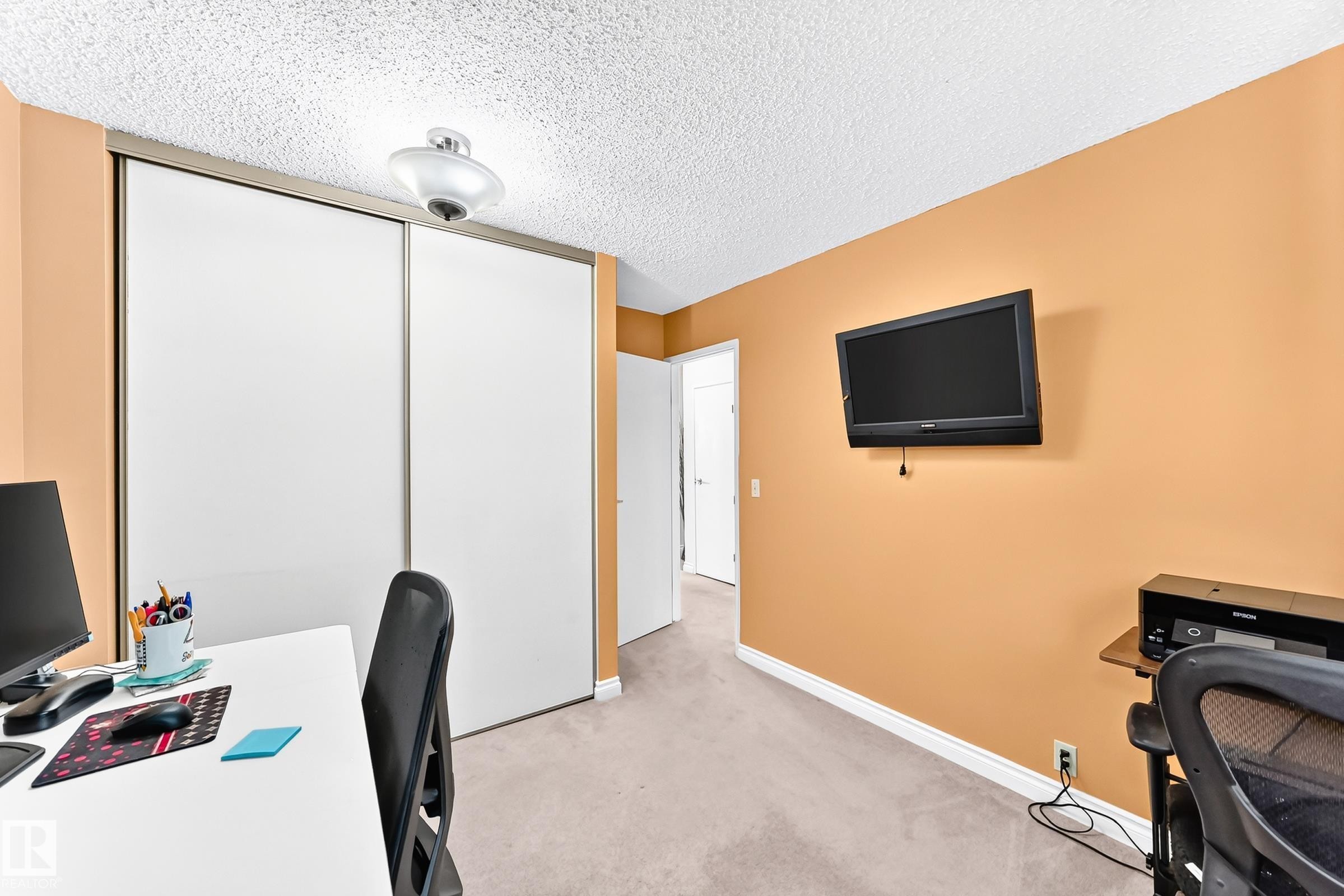 Built-in closet with sliding doors, neutral carpeting, and a ceiling-mounted light fixture - 5620 93A Avenue Nw, Edmonton, AB