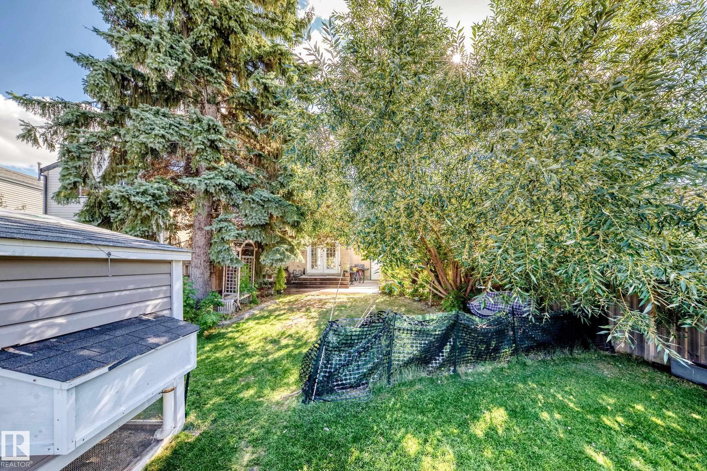 Expansive backyard with a manicured lawn, mature trees, and a garden structure - 5620 93A Avenue Nw, Edmonton, AB