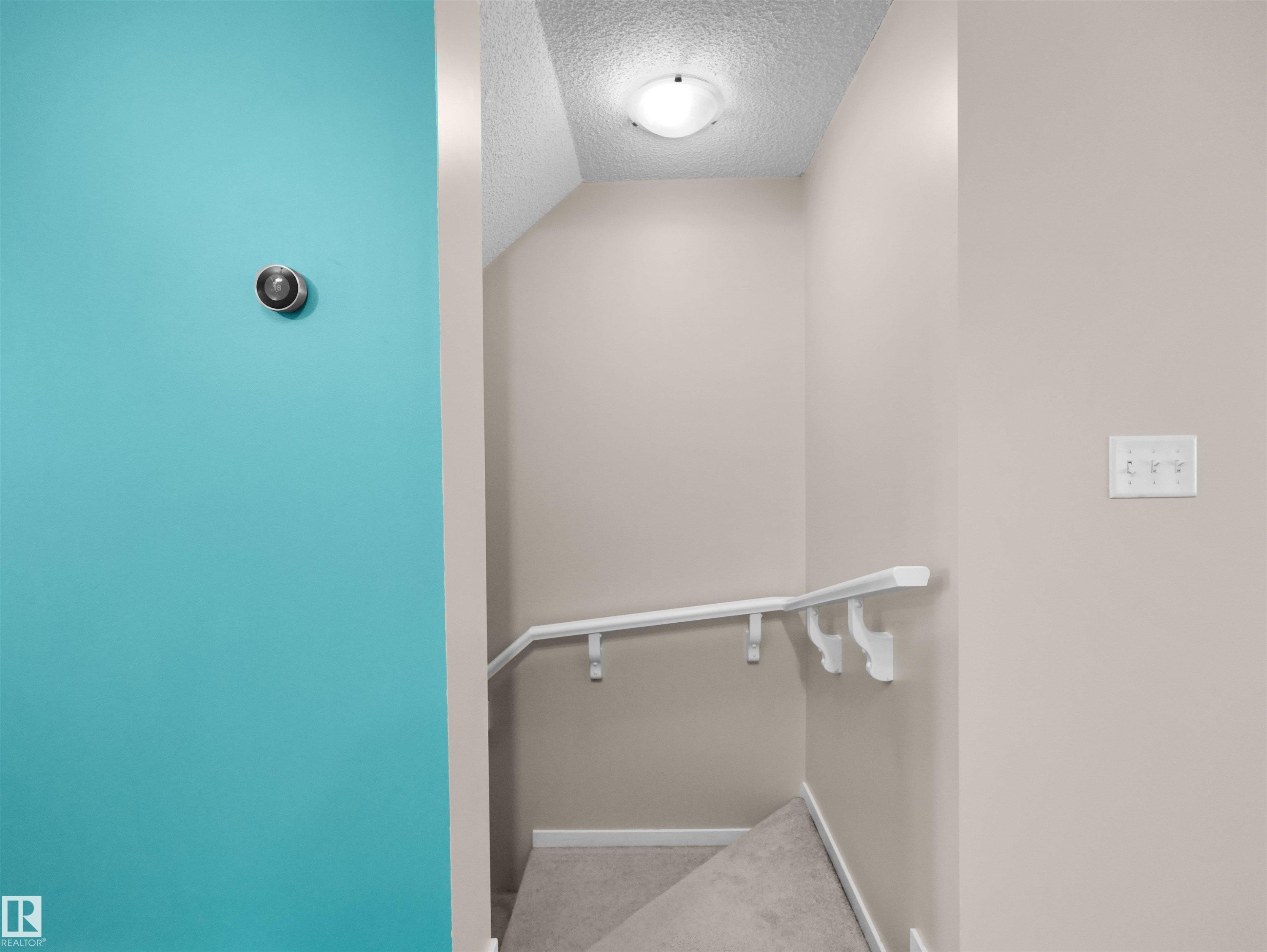 Carpeted staircase with white handrail and neutral wall paint - #162 603 Watt Bv Sw, Edmonton, AB