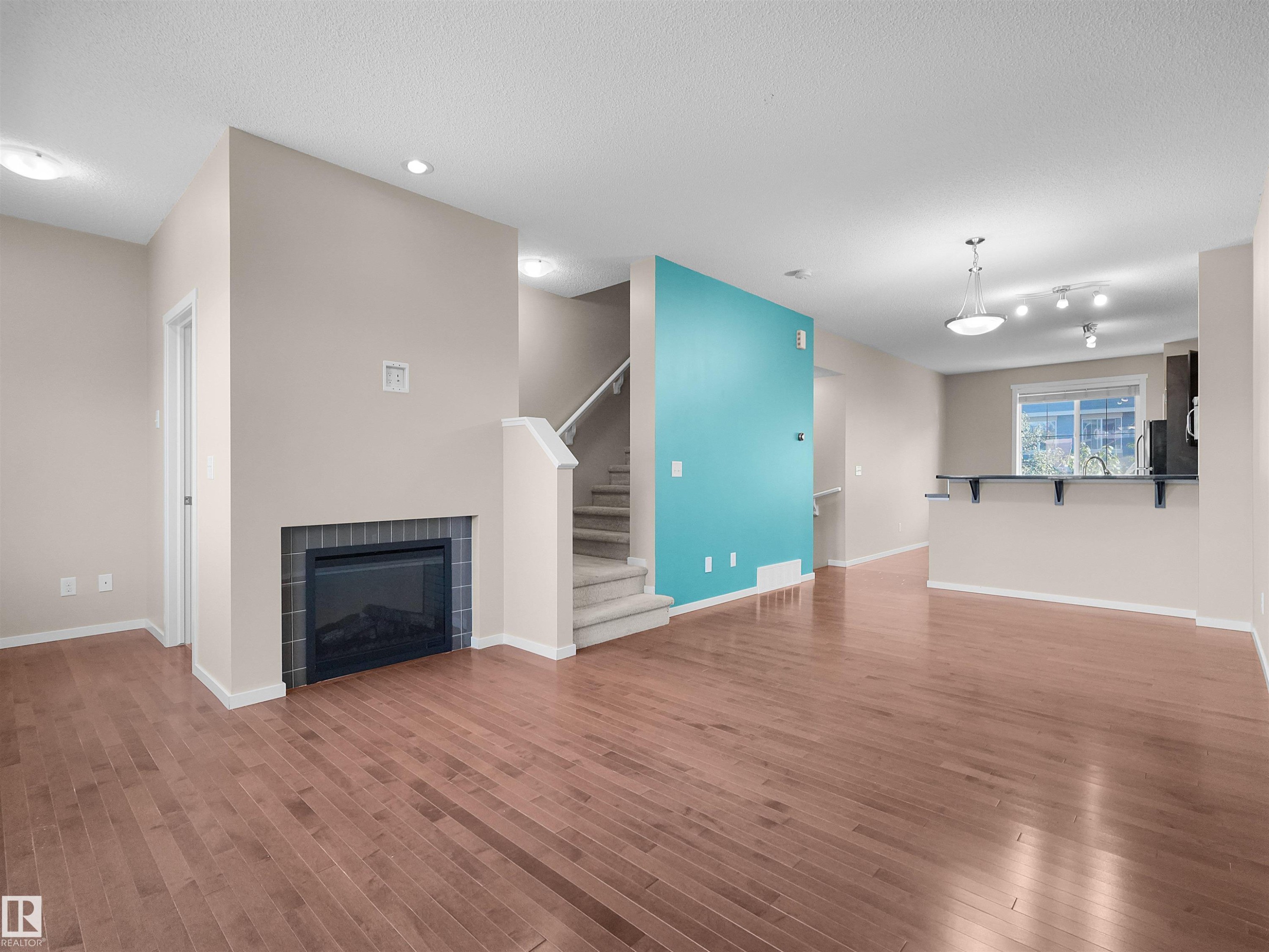Hardwood flooring, fireplace with tile surround, recessed lighting, and kitchen pass-through with countertop - #162 603 Watt Bv Sw, Edmonton, AB