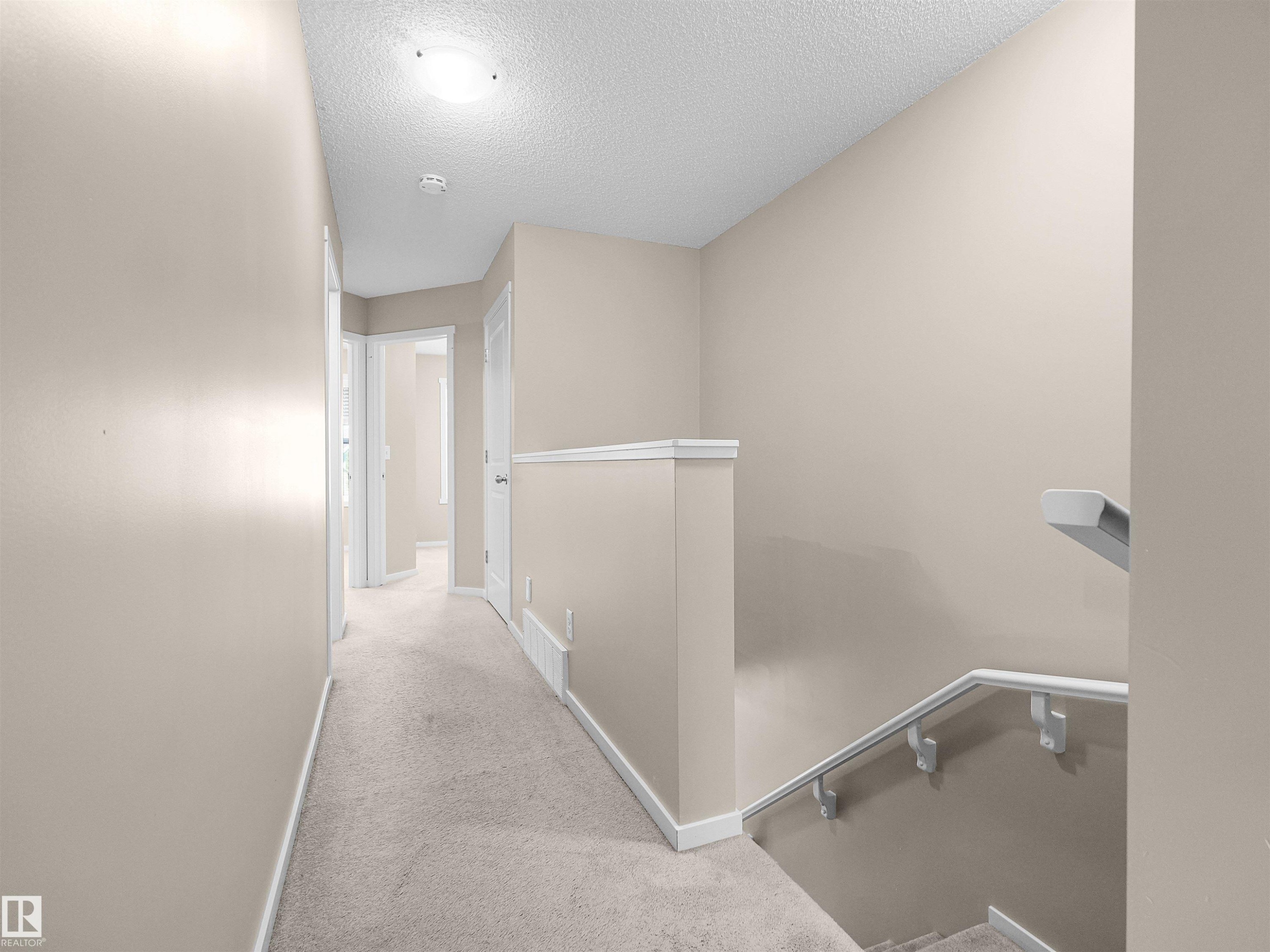 Carpeted hallway with light neutral wall paint and white trim - #162 603 Watt Bv Sw, Edmonton, AB