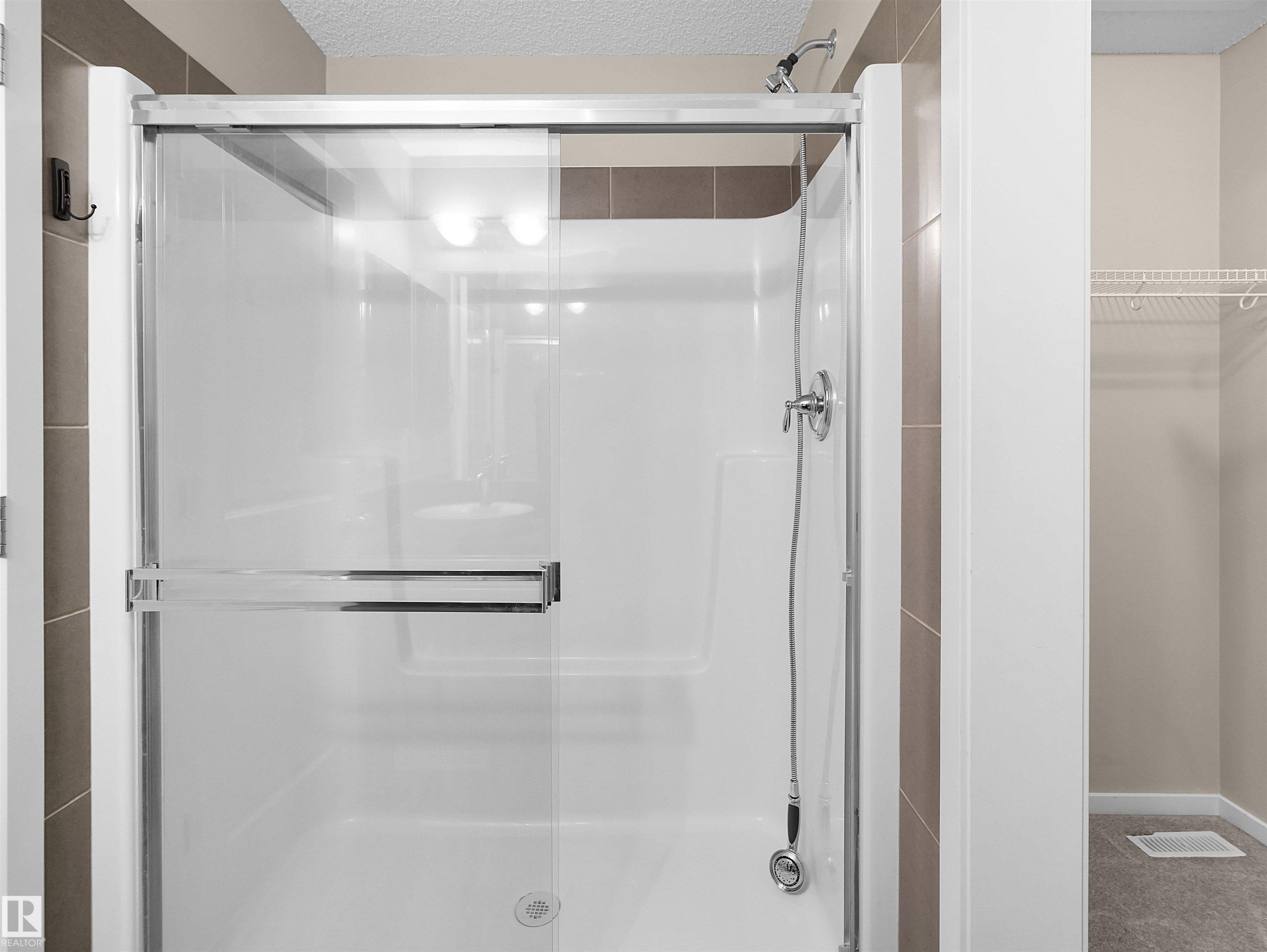 Shower enclosure with sliding glass door, chrome hardware, and a built-in shelf - #162 603 Watt Bv Sw, Edmonton, AB