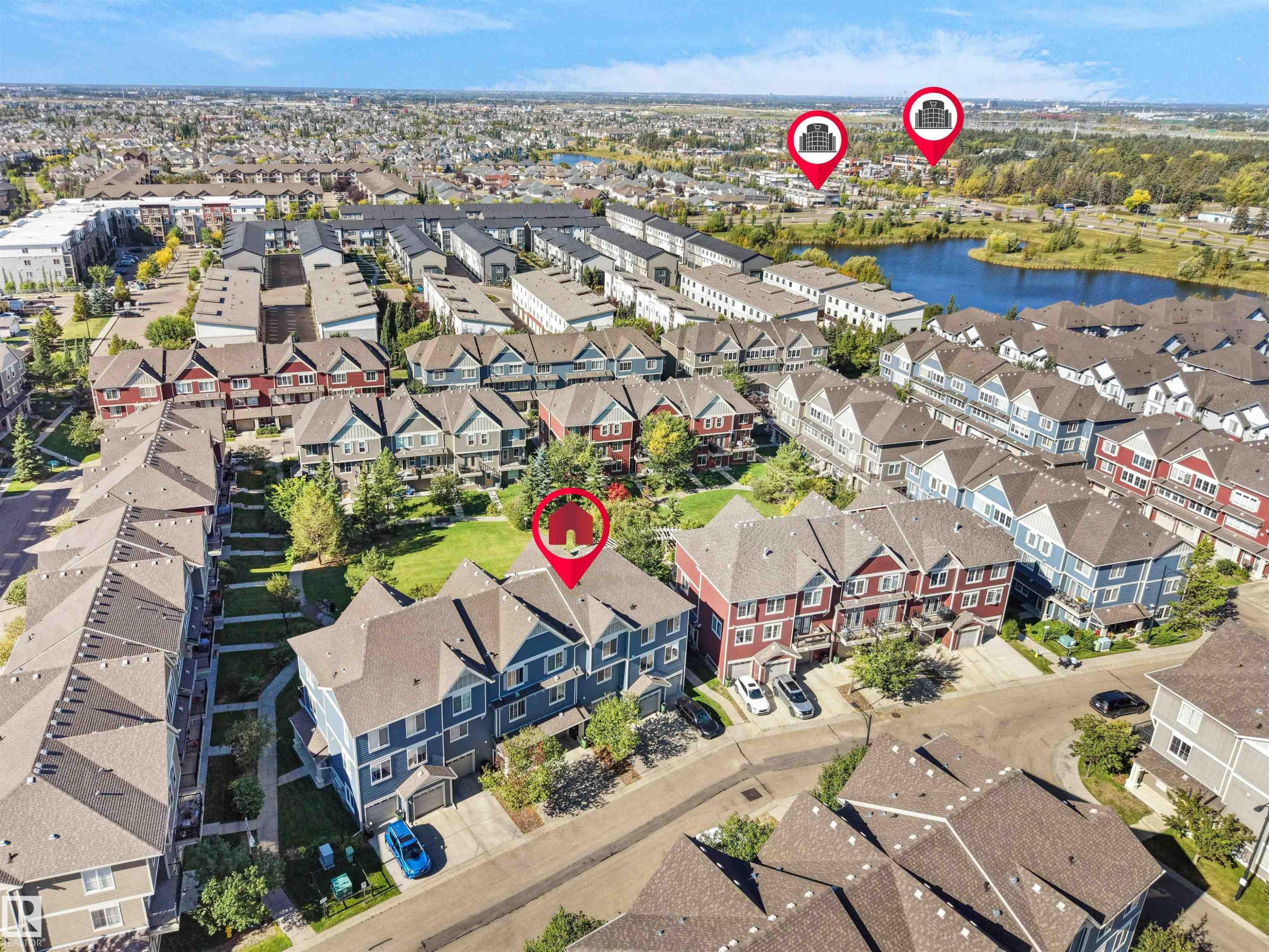 Townhouse community featuring diverse architectural styles, landscaped green spaces, and a nearby body of water - #162 603 Watt Bv Sw, Edmonton, AB