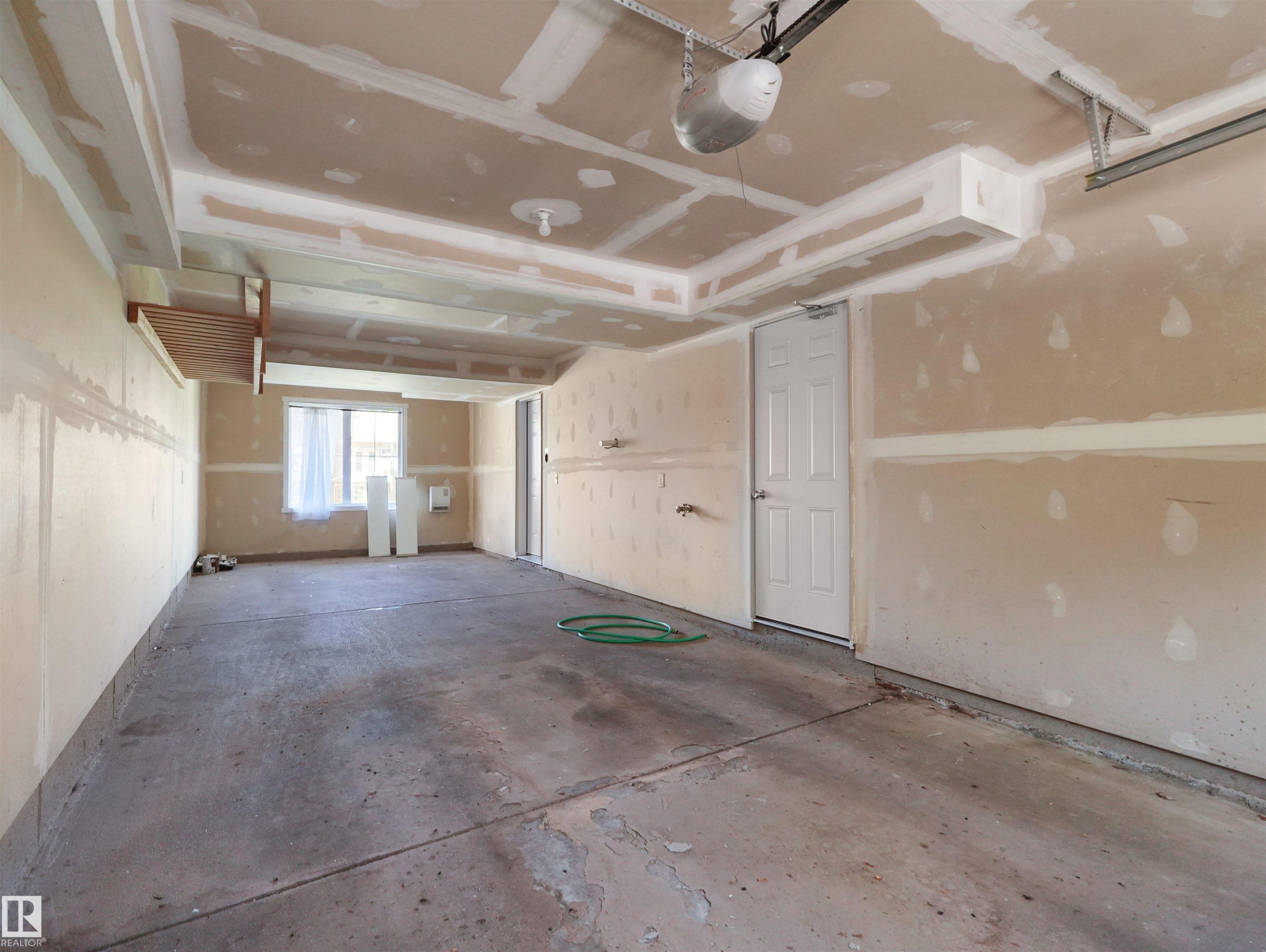 Window with natural light, concrete flooring, overhead garage door mechanism, and interior access door - #162 603 Watt Bv Sw, Edmonton, AB