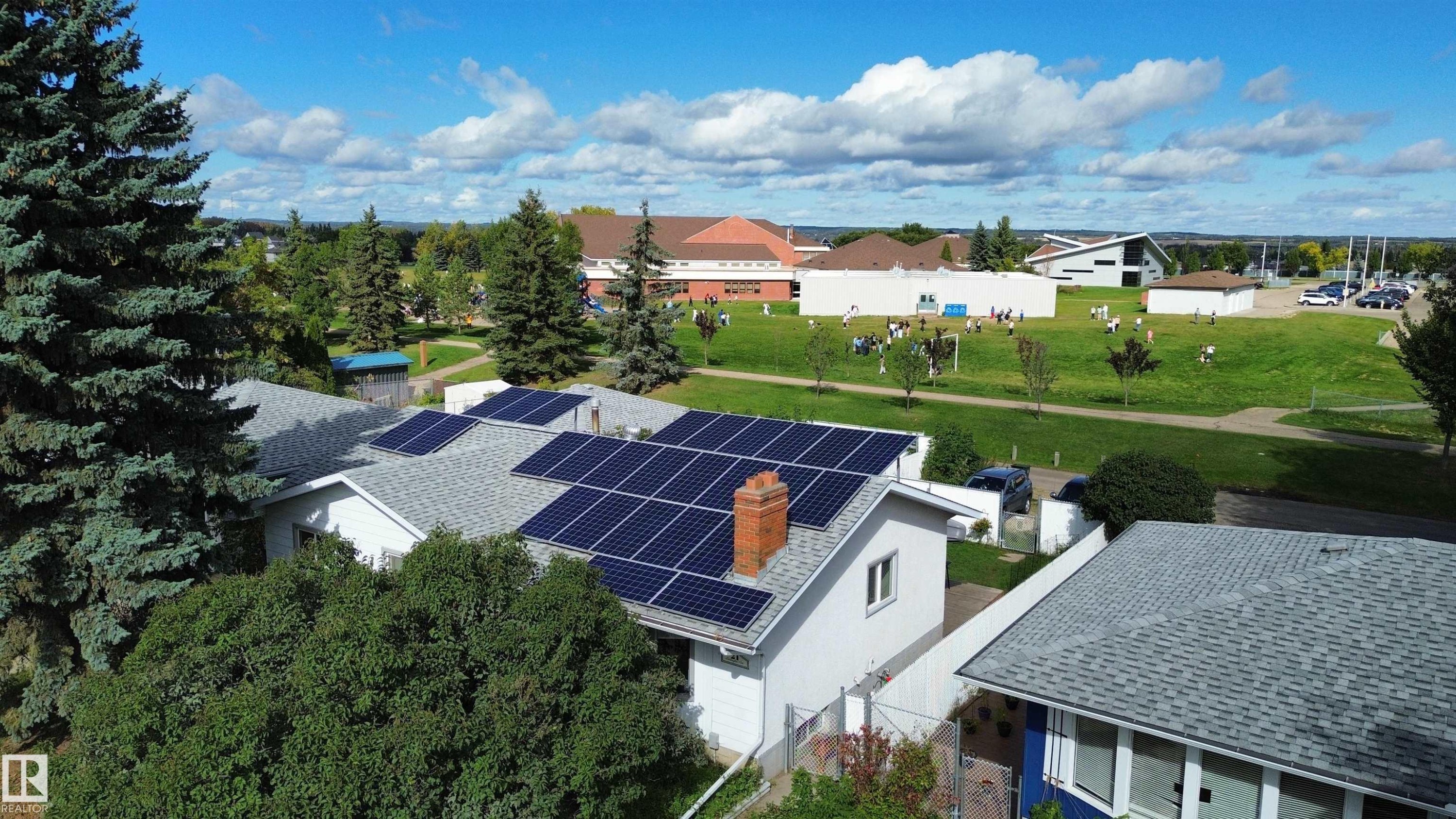 Solar panel system installed on a shingled roof, featuring a brick chimney - 21 Burlington Avenue, Spruce Grove, AB