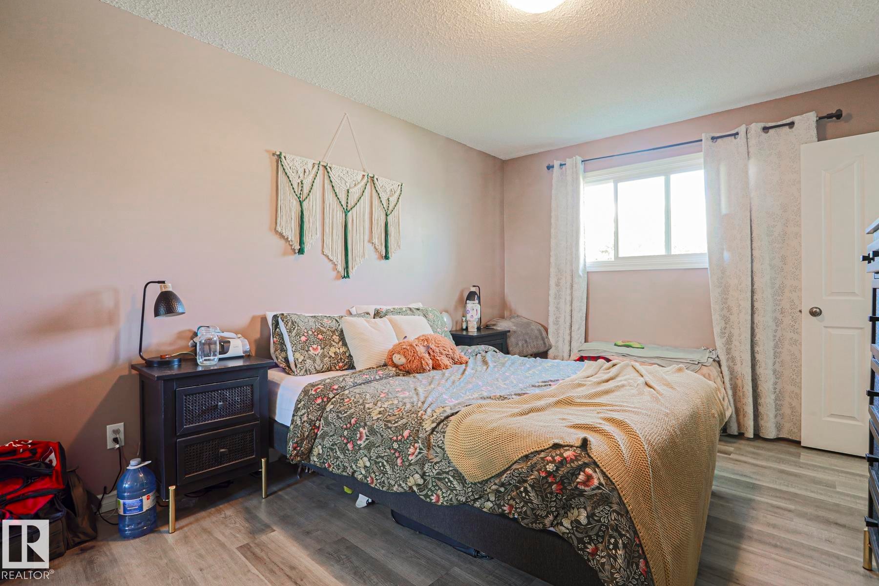 Light wood-finish flooring with a white trim window and white door - 21 Burlington Avenue, Spruce Grove, AB