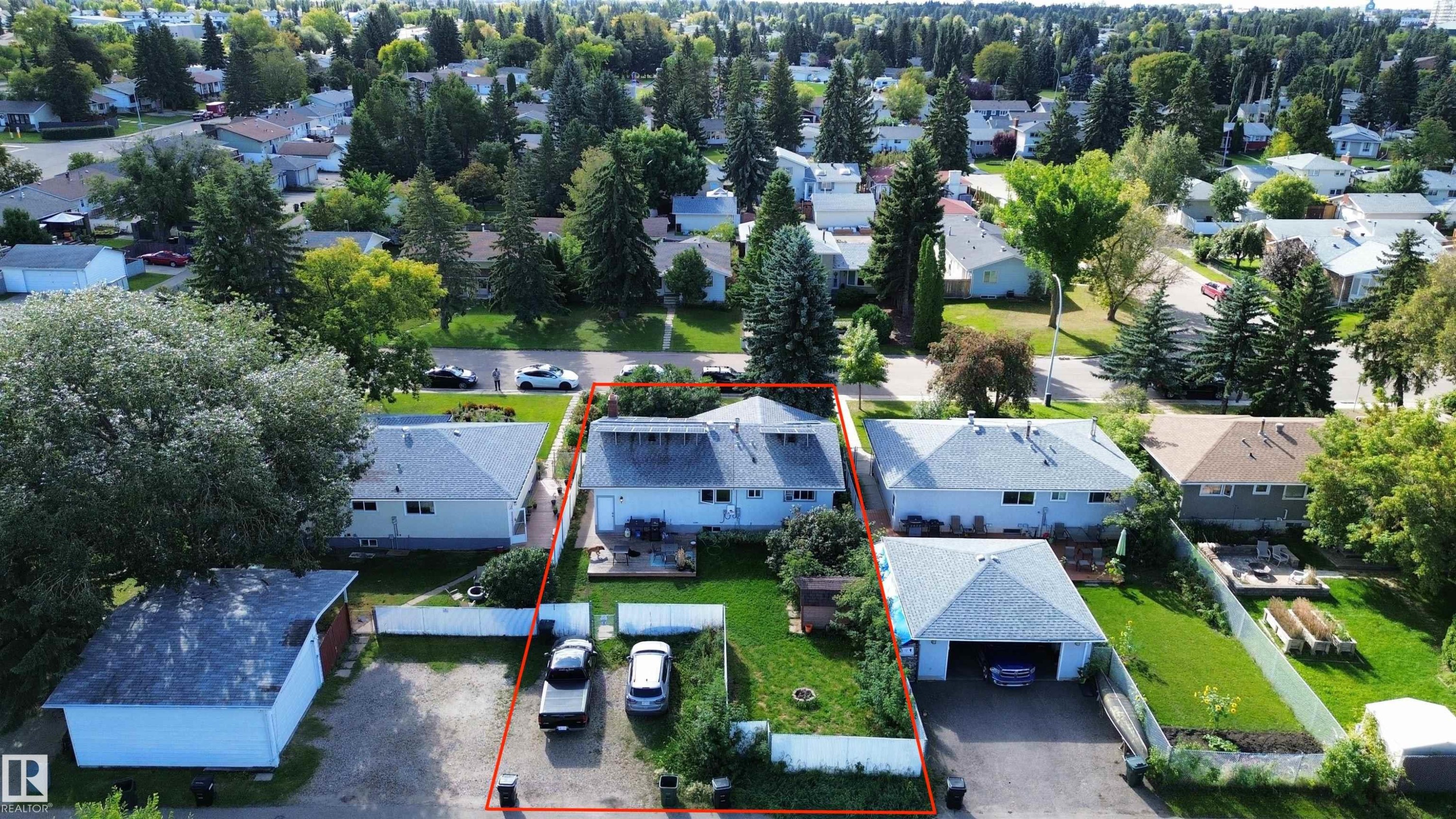 Single-story residence with a light-colored exterior and a gabled roof, featuring a detached garage with a paved driveway - 21 Burlington Avenue, Spruce Grove, AB