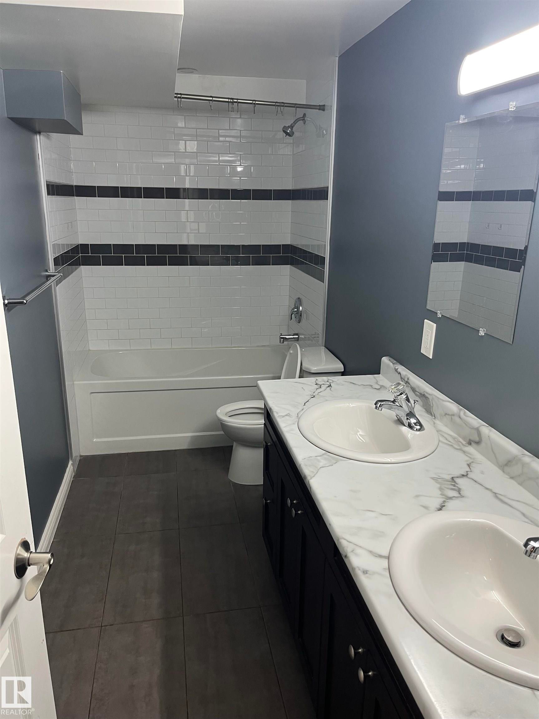 Dual vanity with white undermount sinks, a marble-patterned countertop, and dark cabinetry - 21 Burlington Avenue, Spruce Grove, AB
