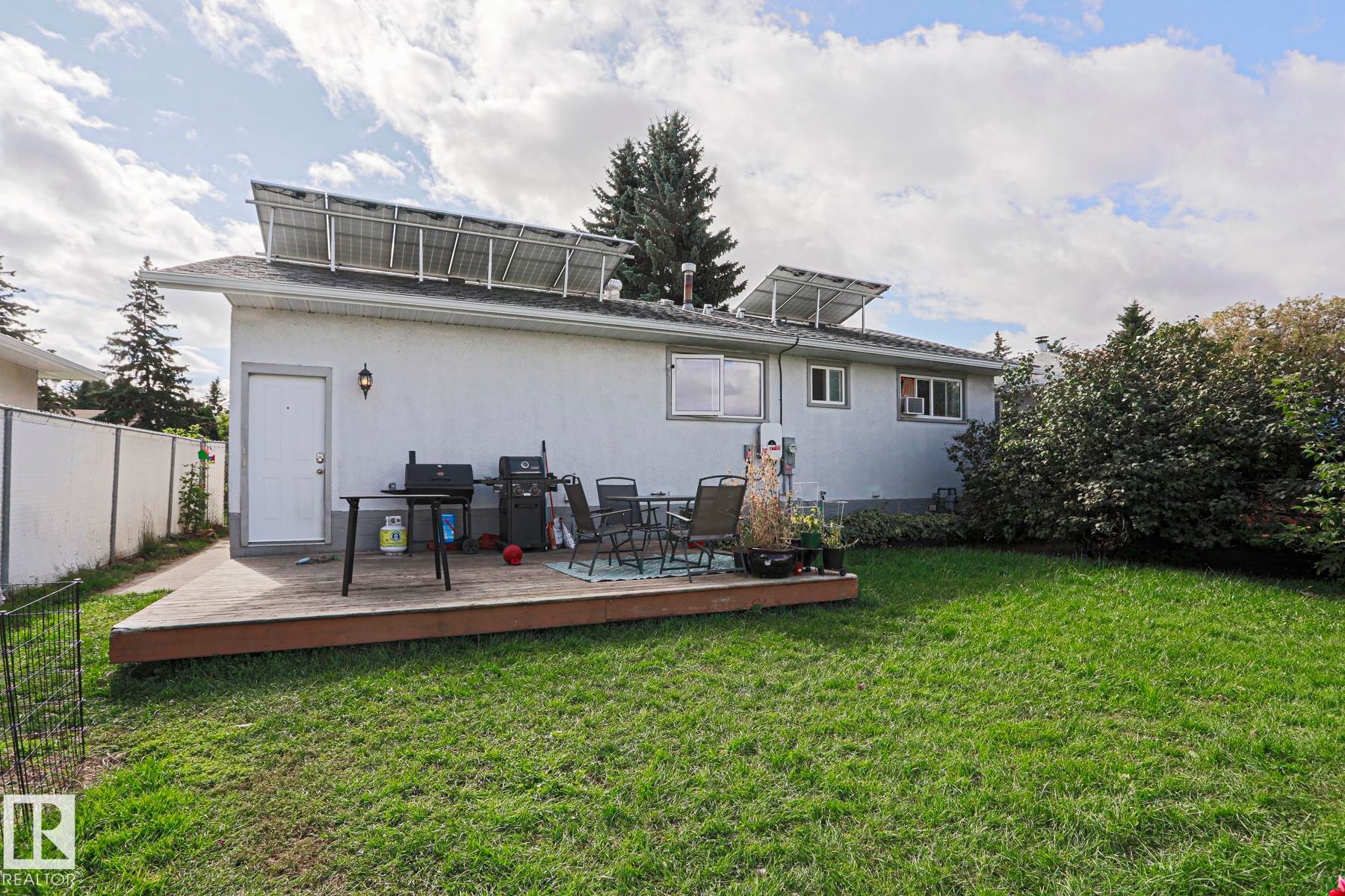 Rear exterior with solar panels, a wooden deck, and a grass lawn - 21 Burlington Avenue, Spruce Grove, AB