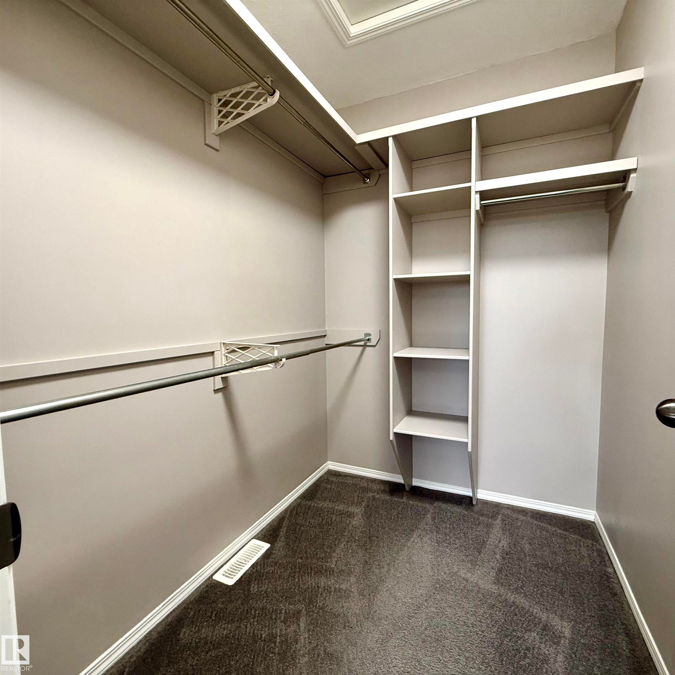 Built-in shelving, hanging rods, and dark carpeting - 910 Oakland Boulevard, Devon, AB