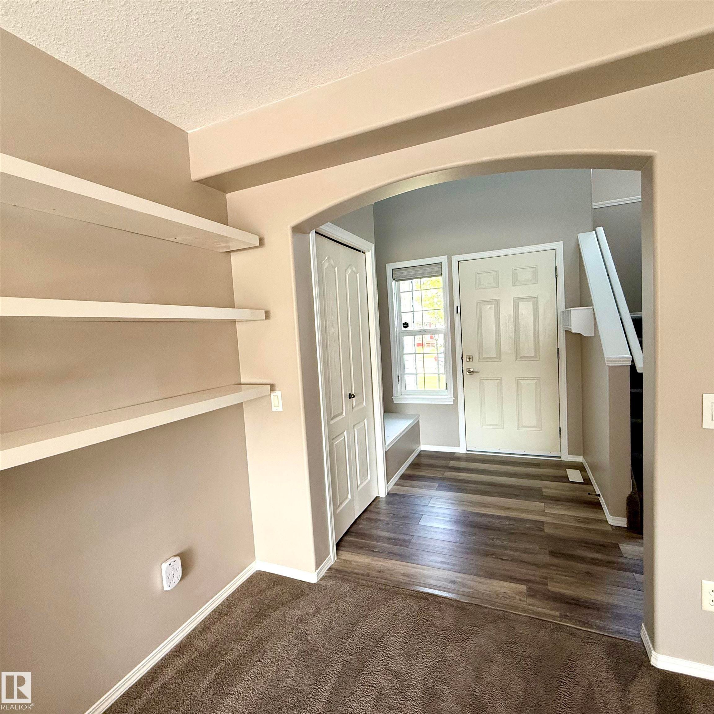 Archway entry featuring built-in shelving, wood-finish flooring, built-in window seating, and a paneled front door - 910 Oakland Boulevard, Devon, AB