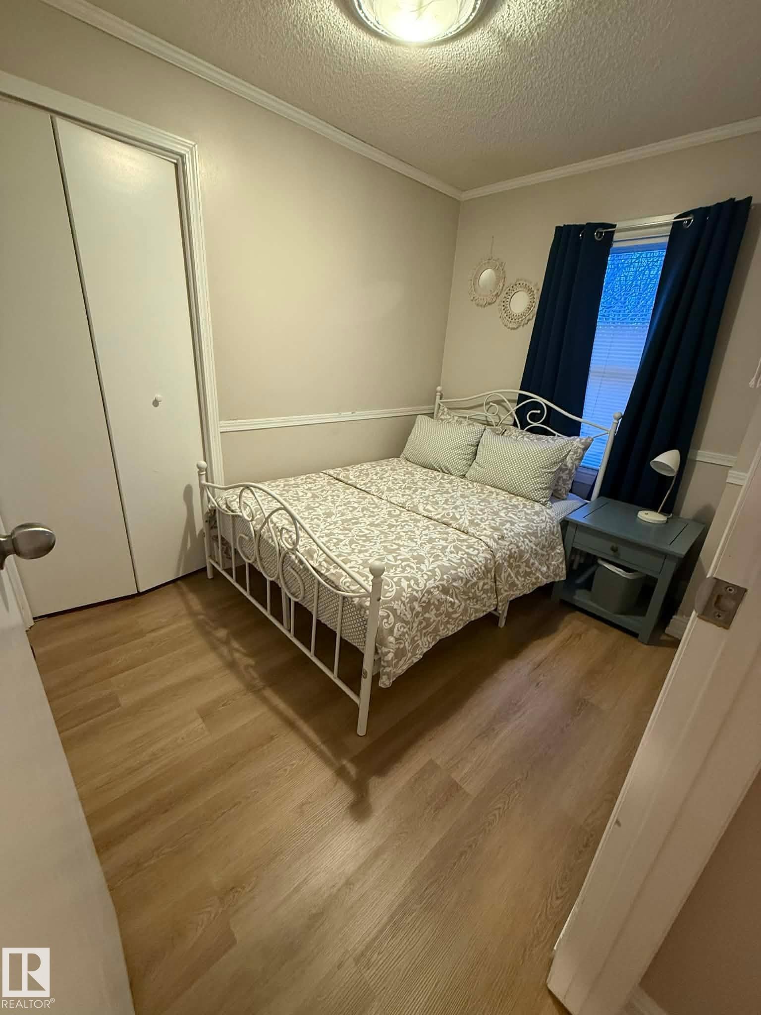 Wood-finish flooring throughout, complemented by a white bi-fold closet door - 10649 125 Street Nw, Edmonton, AB
