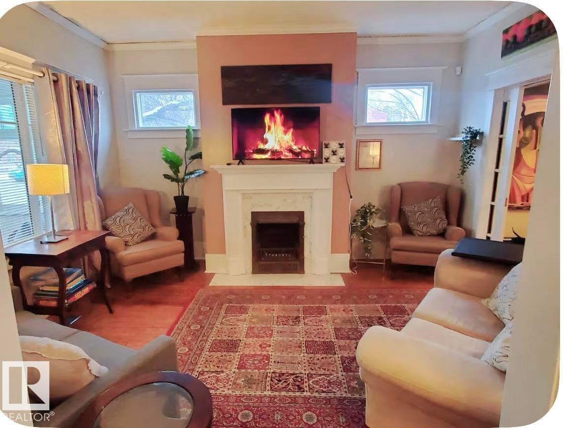 Central fireplace with a classic white mantel, wood-finish flooring, and multiple windows - 10649 125 Street Nw, Edmonton, AB