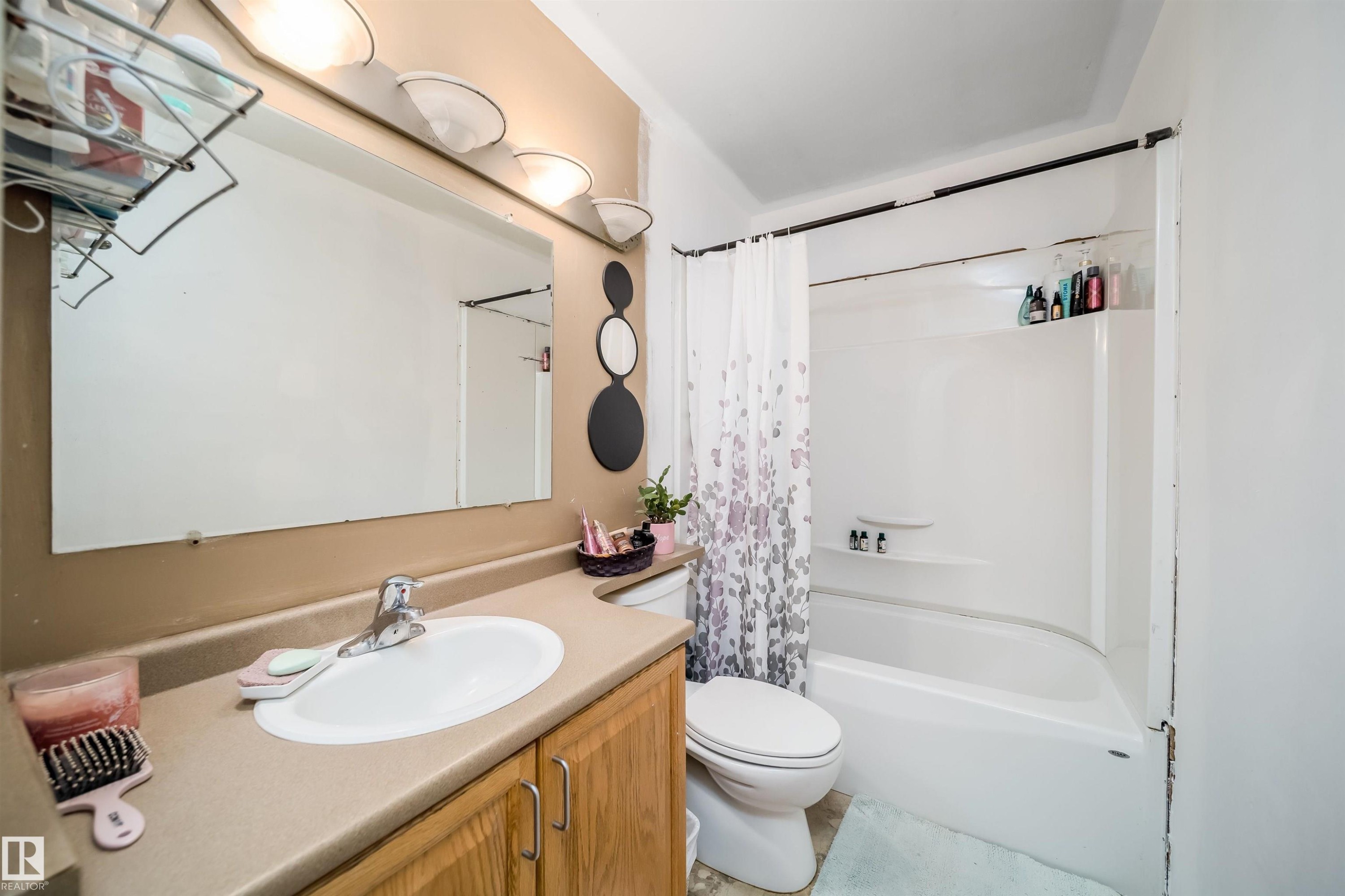 Bathroom featuring a single vanity with wood-finish cabinetry, an oval sink, and a laminate countertop - 4104 44 Street, Stony Plain, AB