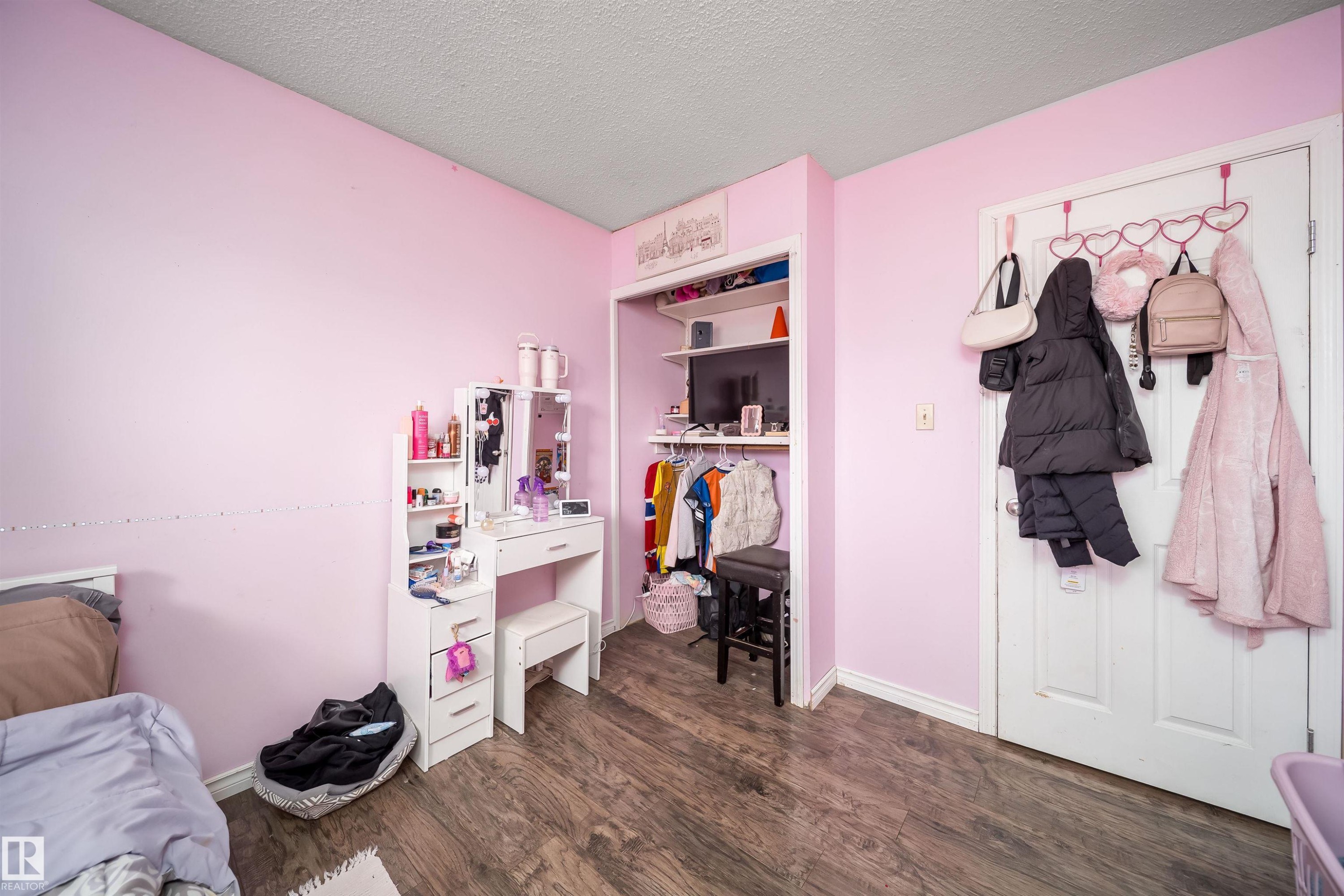Wood-finish flooring with light-colored walls and a built-in closet featuring shelving - 4104 44 Street, Stony Plain, AB