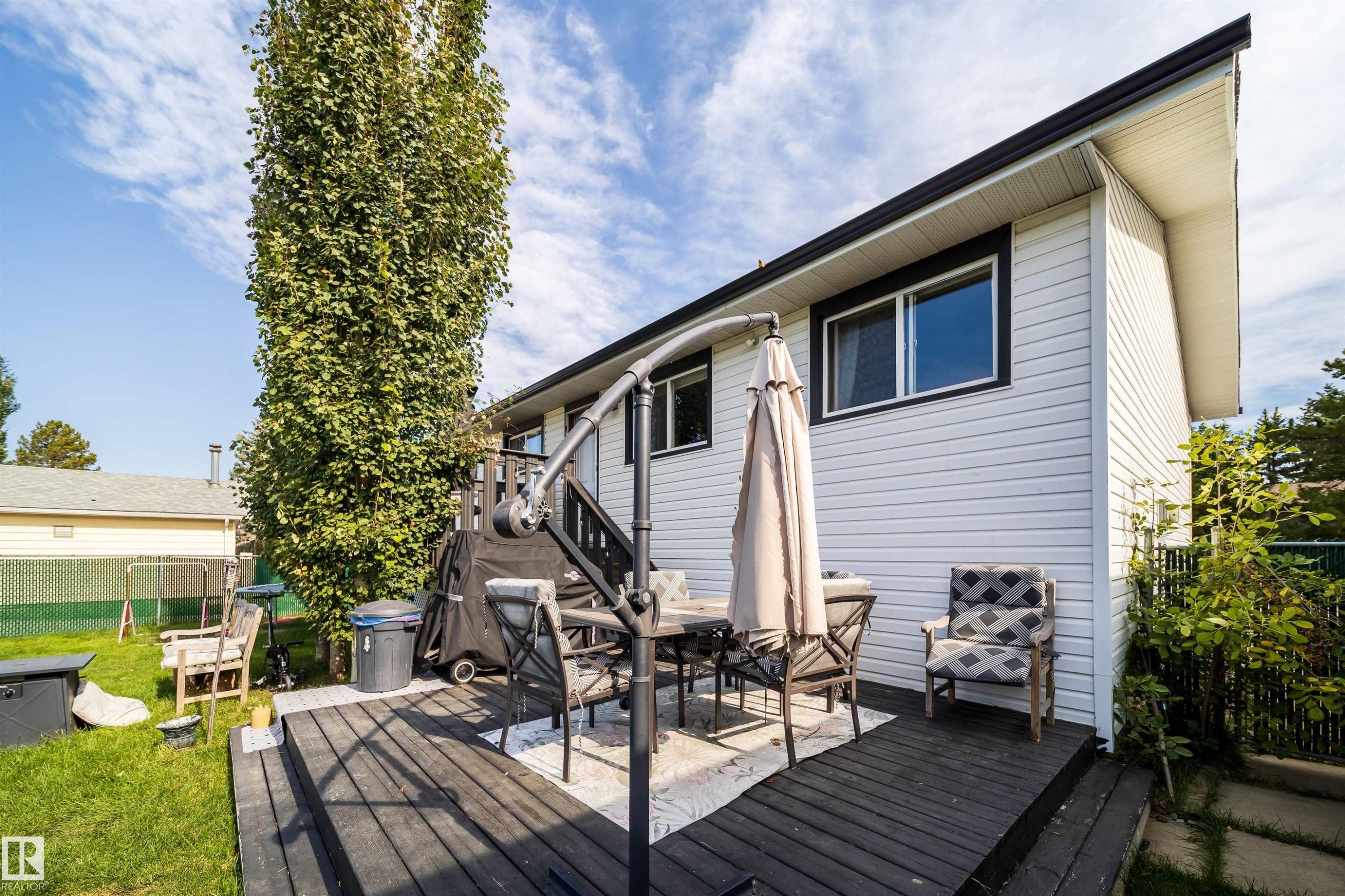 Expansive rear decking with dark wood-finish boards, white horizontal siding, and black trim windows - 4104 44 Street, Stony Plain, AB