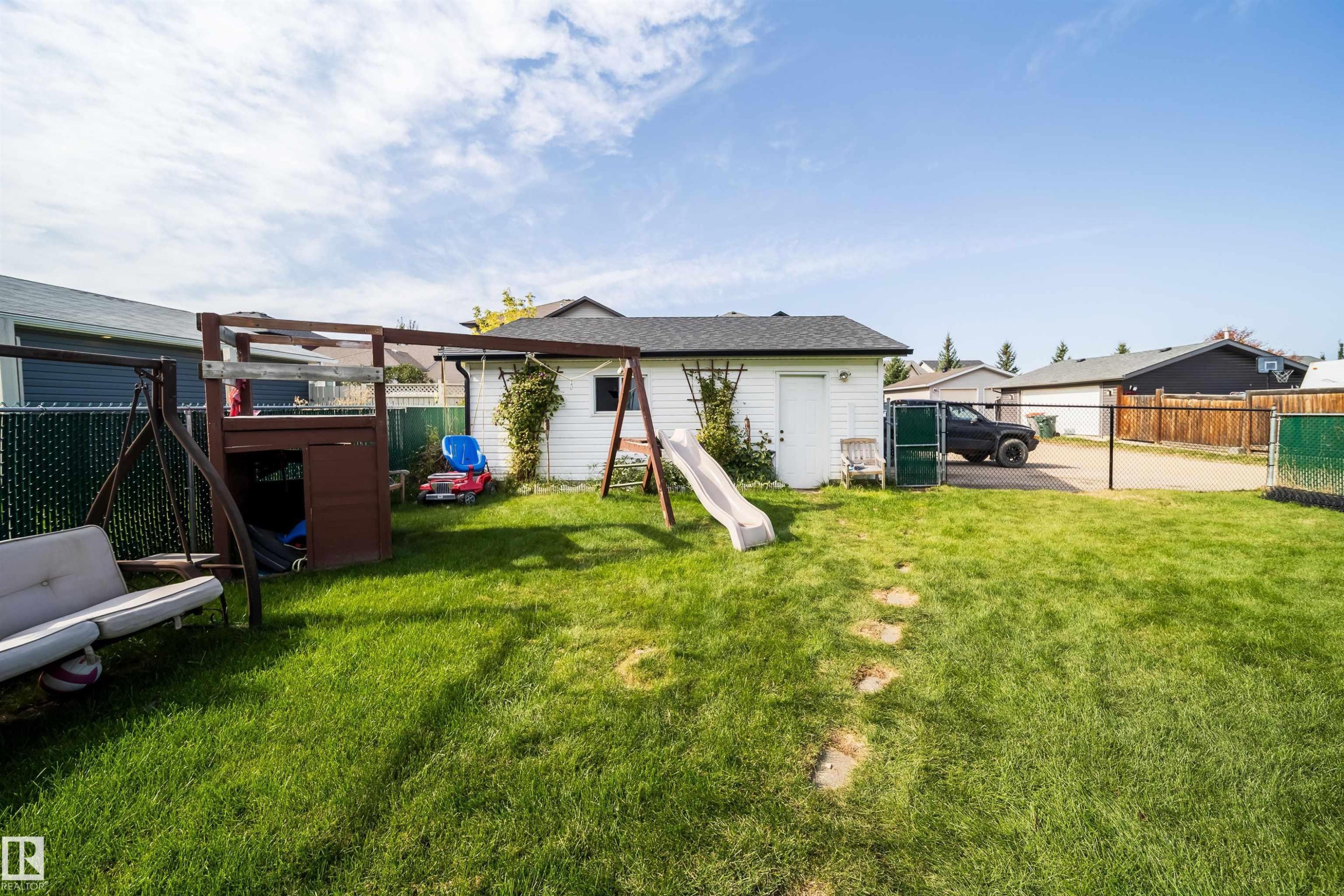 Expansive grassy yard with a white shed, a chain-link fence, and a wooden fence - 4104 44 Street, Stony Plain, AB