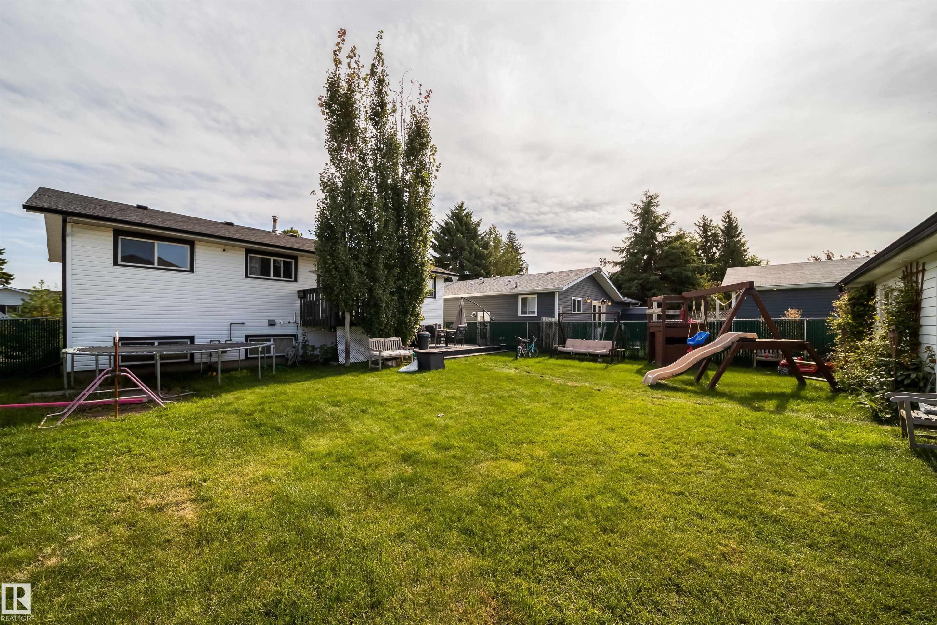 Expansive grassy yard with mature trees and a rear deck - 4104 44 Street, Stony Plain, AB