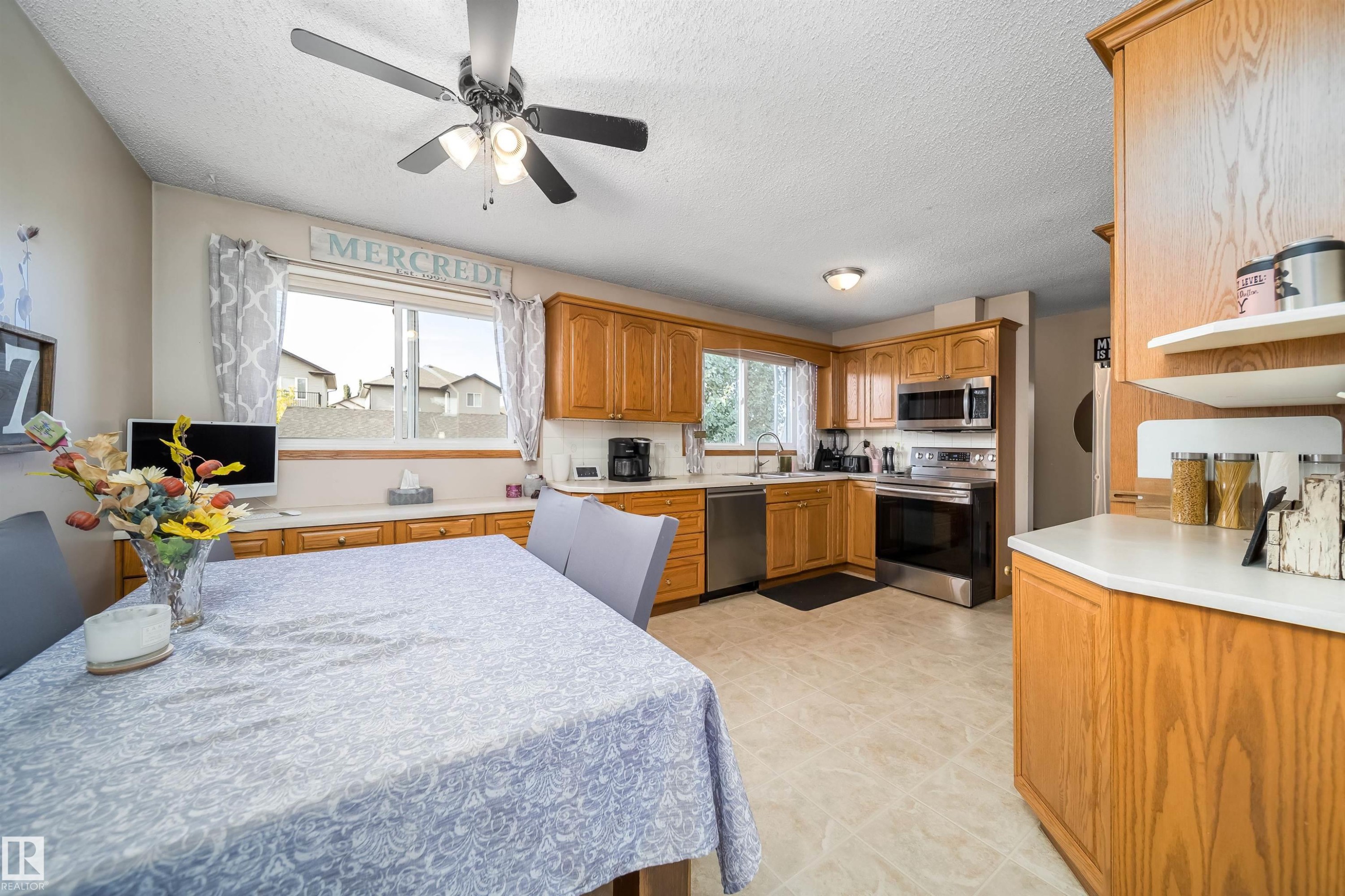 Wood-finish cabinetry, stainless steel appliances, and a ceiling fan with light fixture - 4104 44 Street, Stony Plain, AB