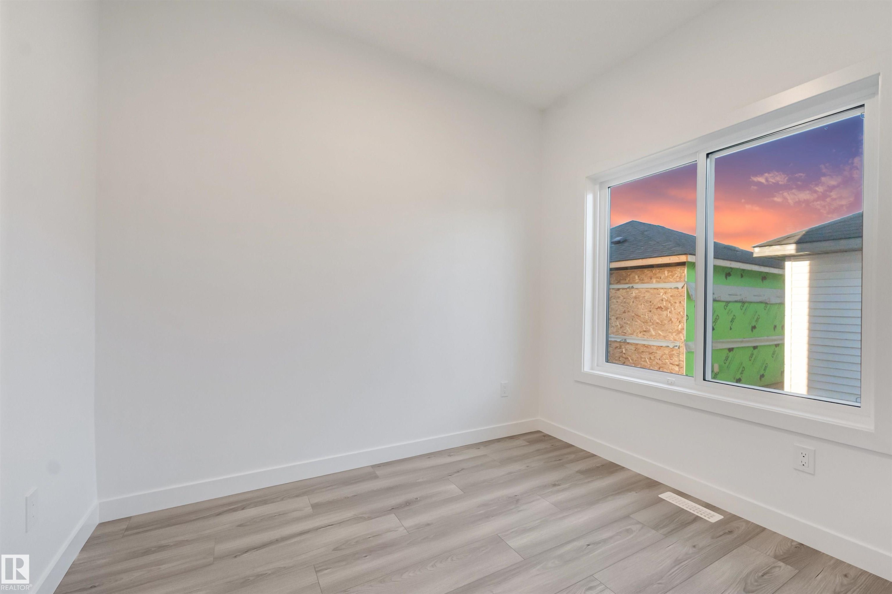 Bright interior with wood-finish flooring, white walls, and a large window - 1515 211 Street Nw, Edmonton, AB