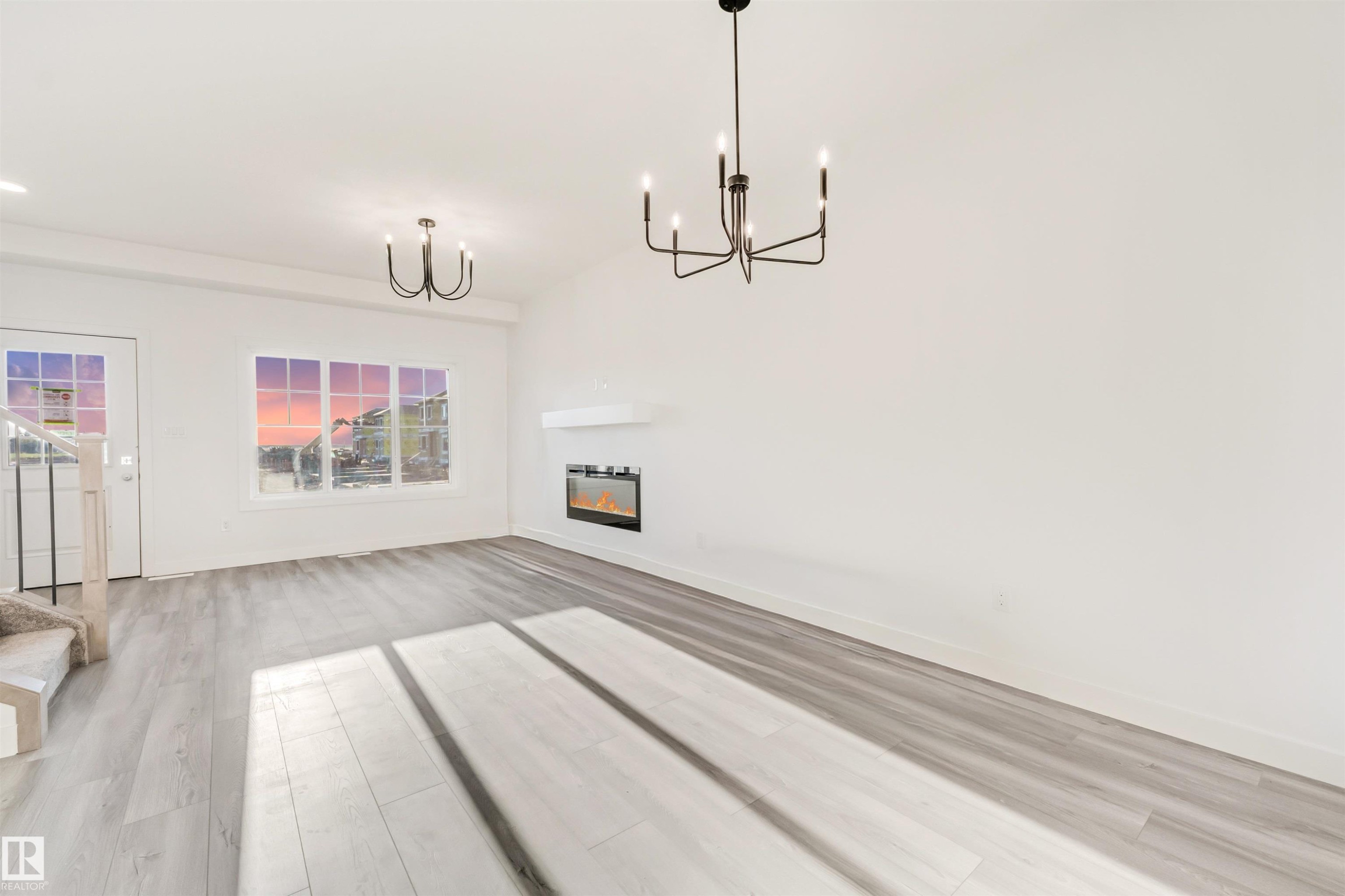 Light wood-finish flooring, white walls, multiple windows, built-in fireplace, and modern light fixtures - 1515 211 Street Nw, Edmonton, AB