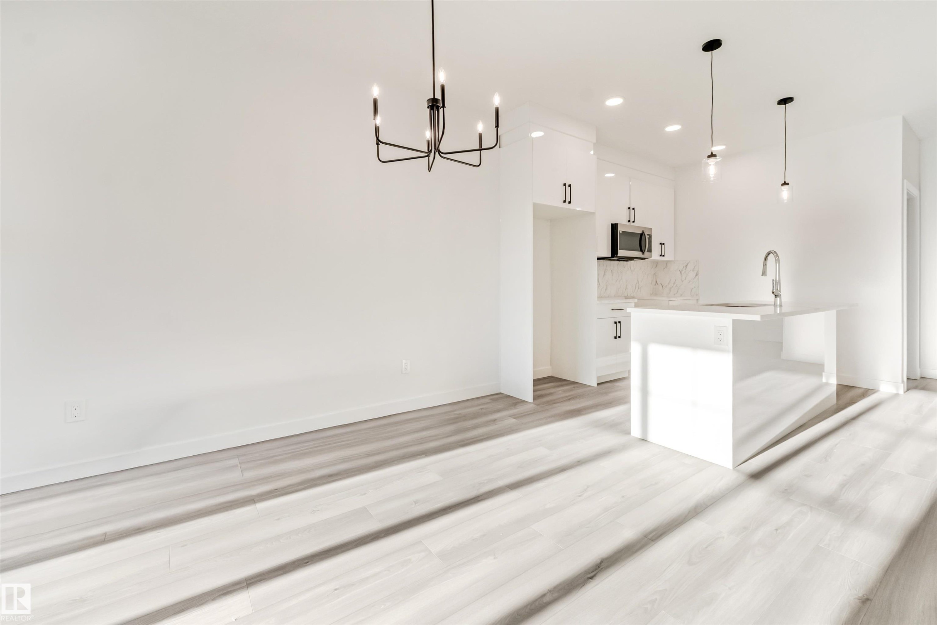White wood-finish flooring throughout, complemented by a modern black chandelier - 1515 211 Street Nw, Edmonton, AB
