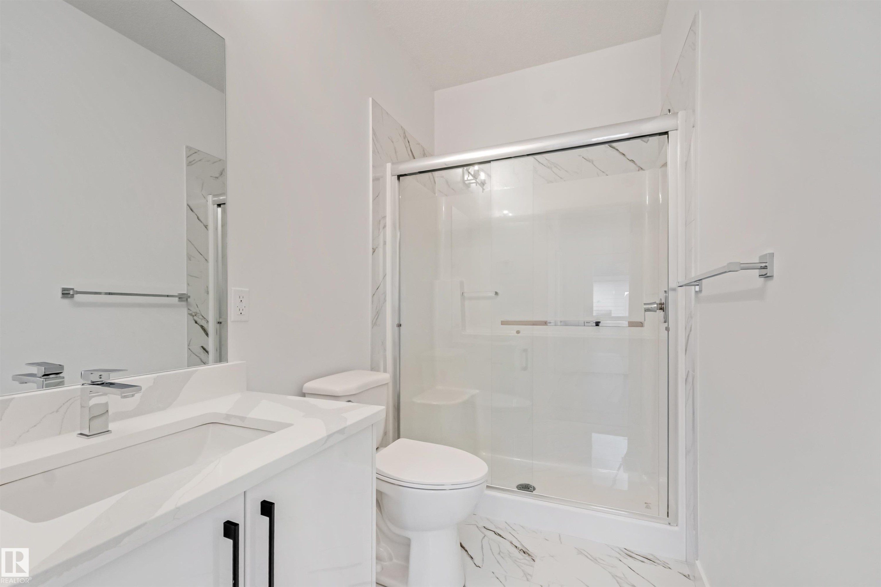 Bathroom featuring a white vanity with integrated sink, chrome faucet, and a wall-mounted mirror - 1515 211 Street Nw, Edmonton, AB