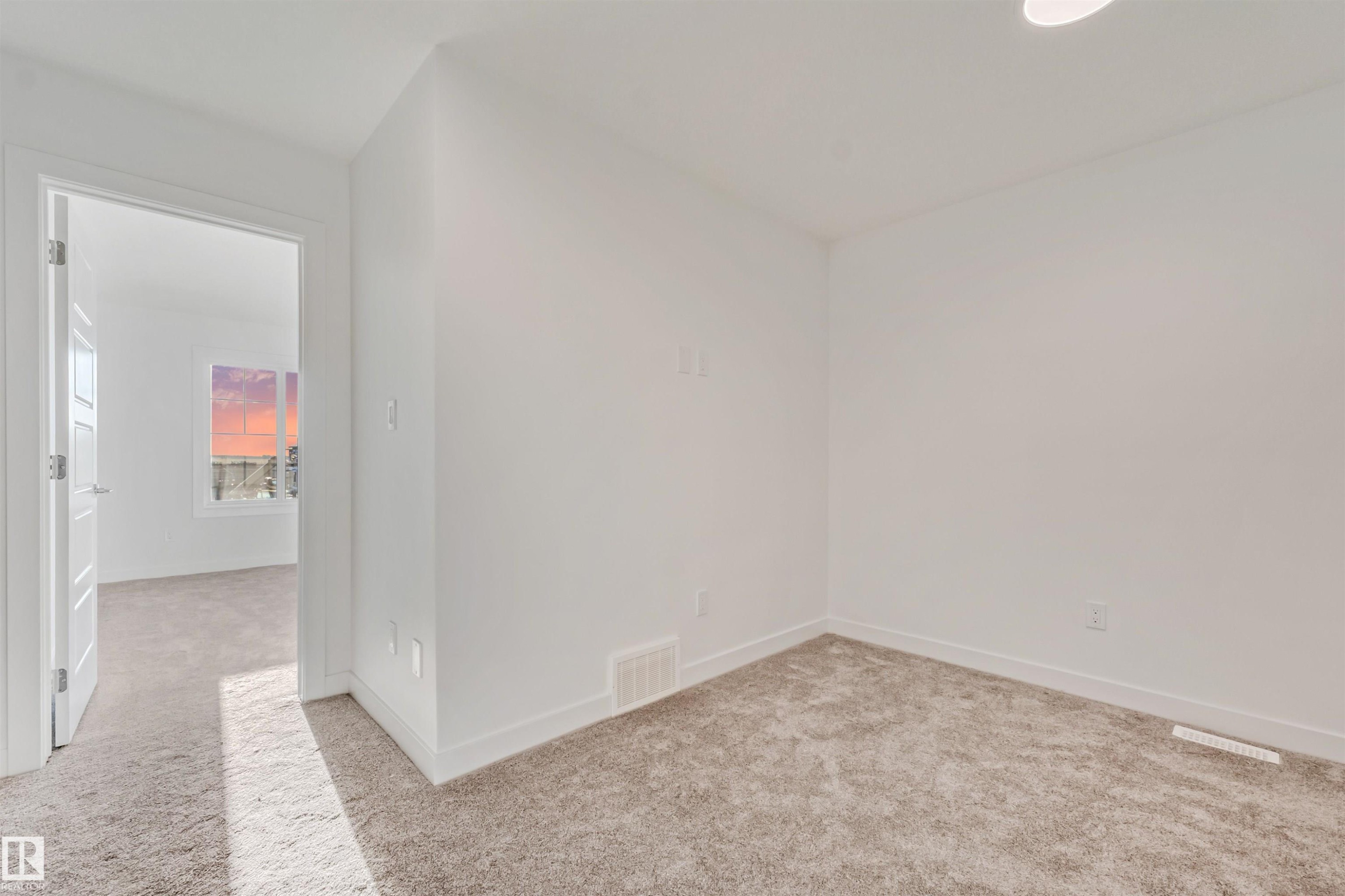 White painted walls, neutral-toned carpet, and a white interior door - 1515 211 Street Nw, Edmonton, AB