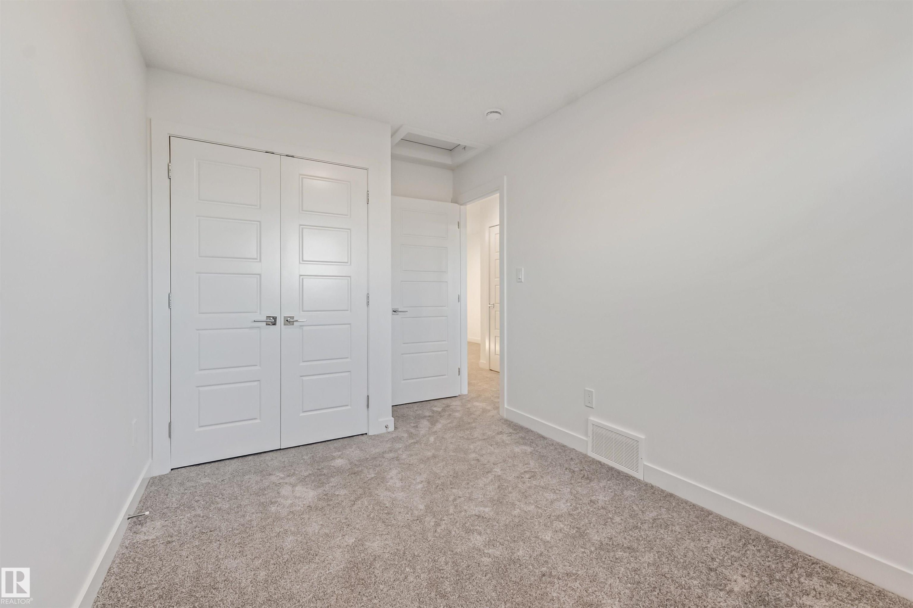 Neutral wall paint, plush carpeting, white trim, and a contemporary four-panel door - 1515 211 Street Nw, Edmonton, AB