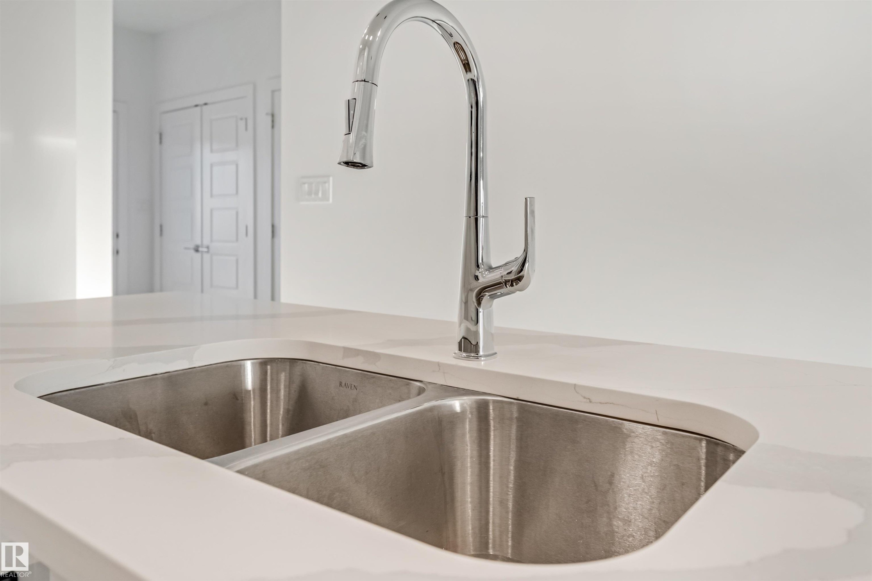 Undermount double basin sink, chrome pull-down faucet, and white countertop with subtle veining - 1515 211 Street Nw, Edmonton, AB