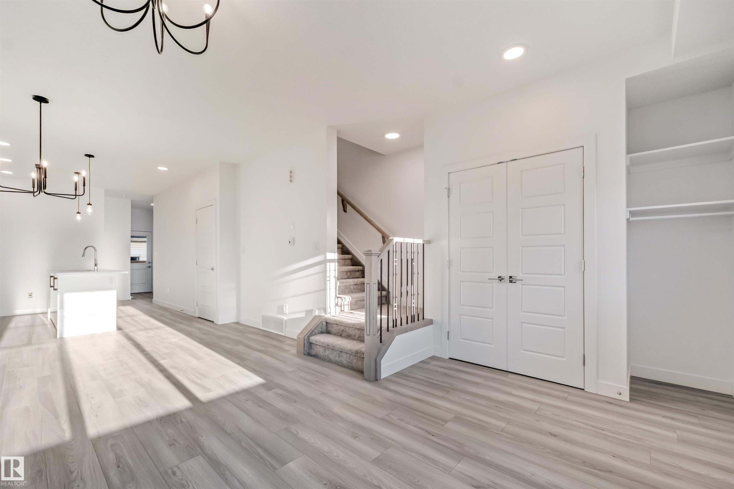 Open-concept living area featuring wood-finish flooring, recessed lighting, and a contemporary chandelier - 1515 211 Street Nw, Edmonton, AB