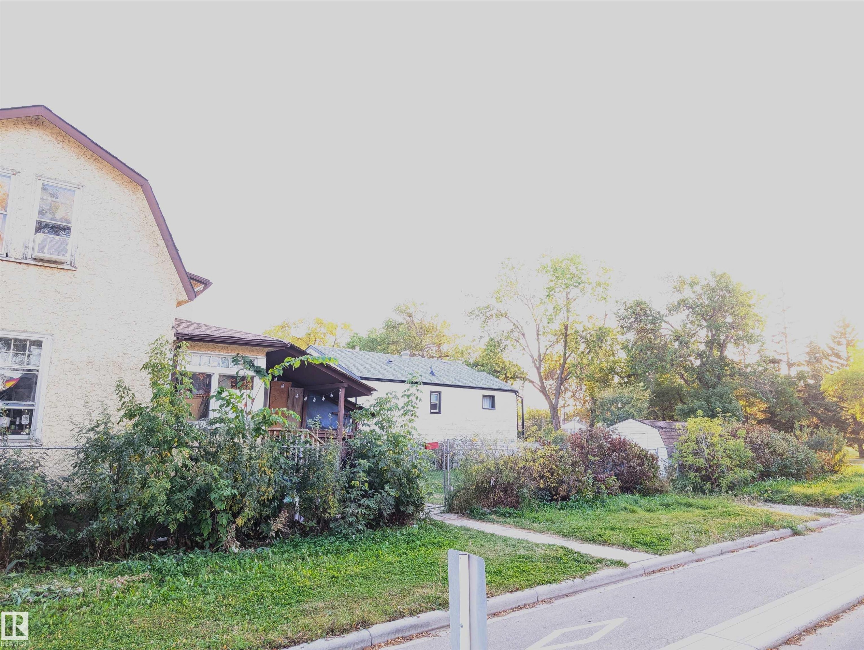 Exterior with stucco finish, covered porch, and mature landscaping - 9115 119 Avenue Nw, Edmonton, AB