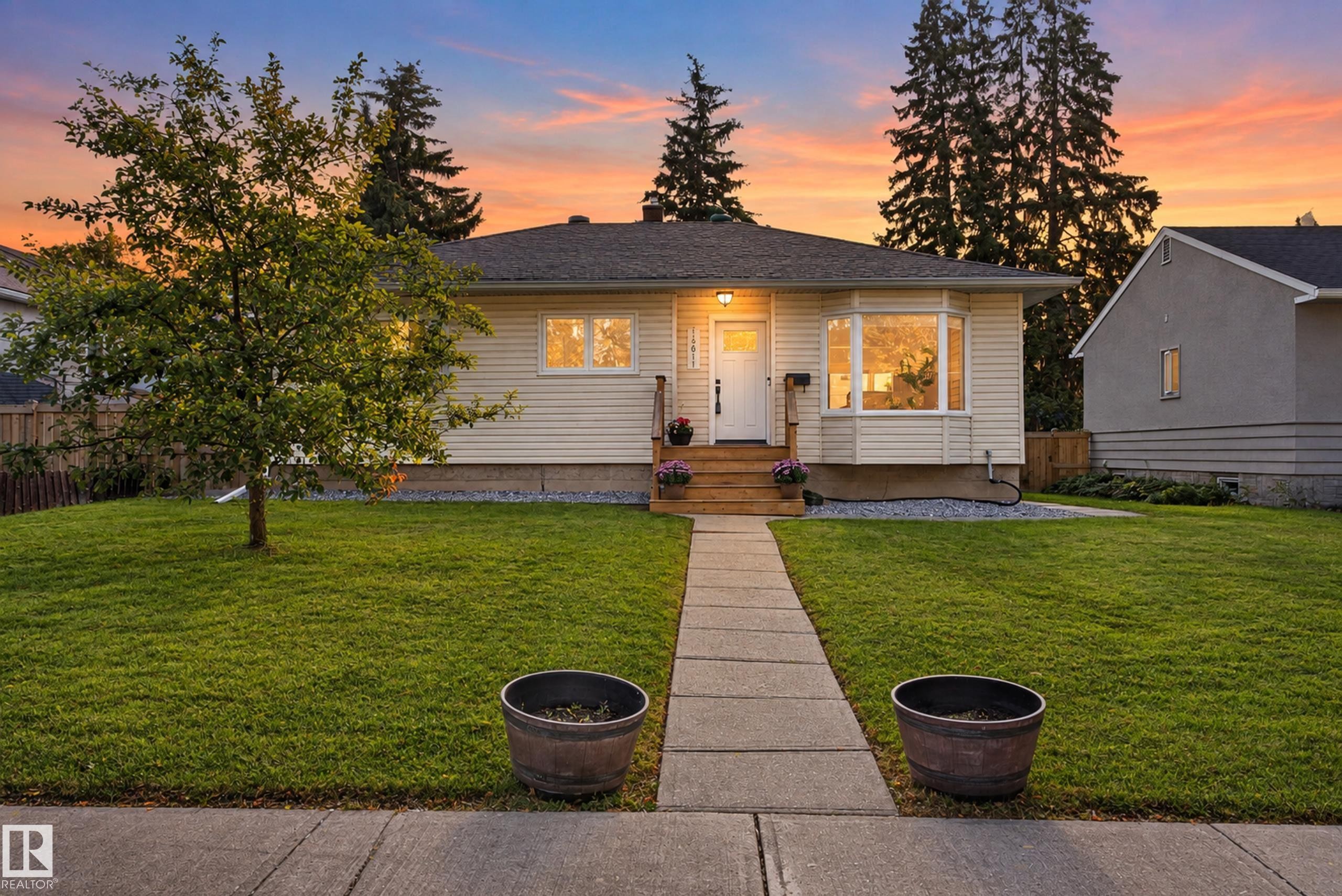 Single-story residence featuring light-colored siding, a prominent bay window, and a concrete pathway - 14611 109 Avenue Nw, Edmonton, AB