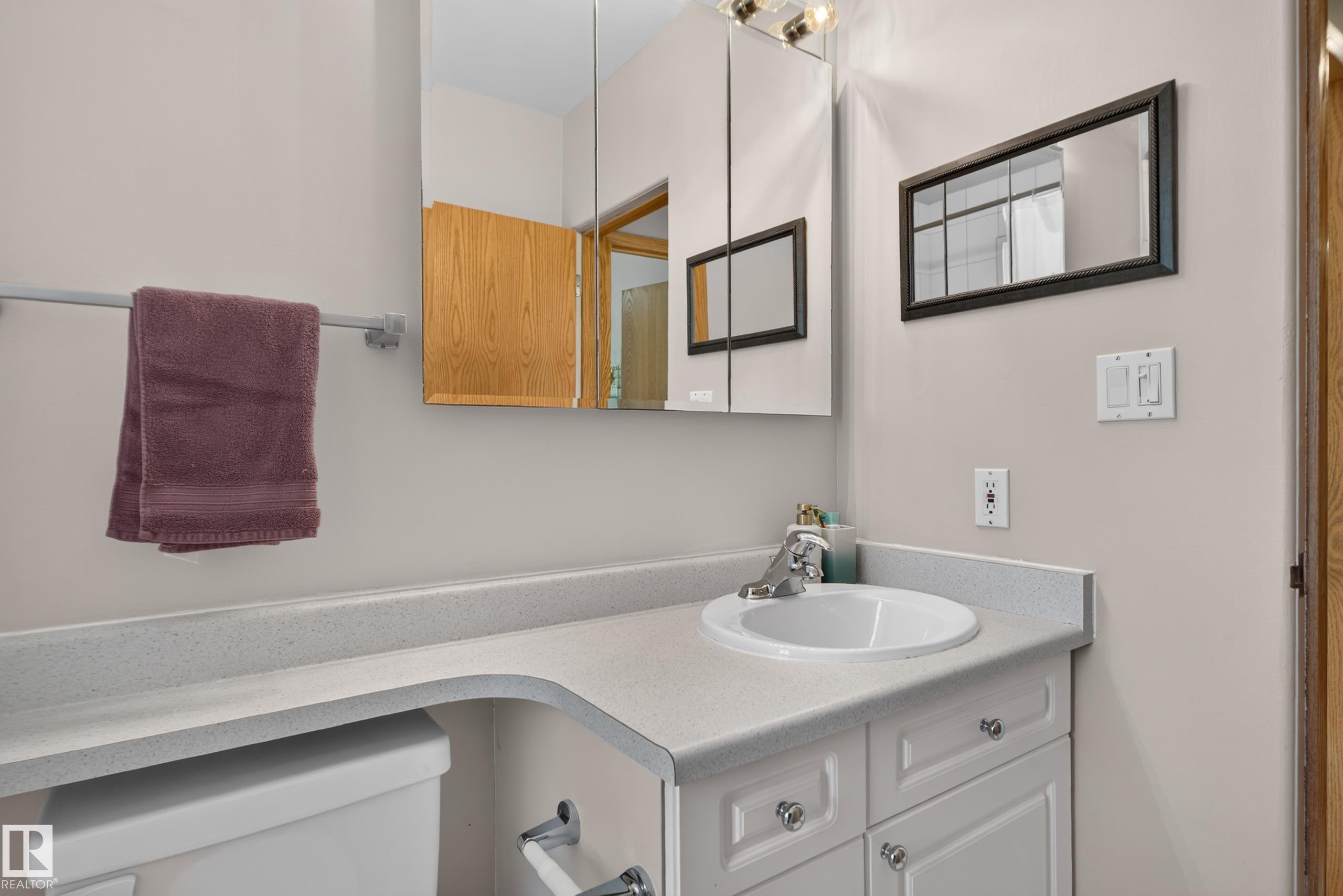 White vanity with silver-tone hardware, an integrated sink, and a light-toned countertop - 14611 109 Avenue Nw, Edmonton, AB