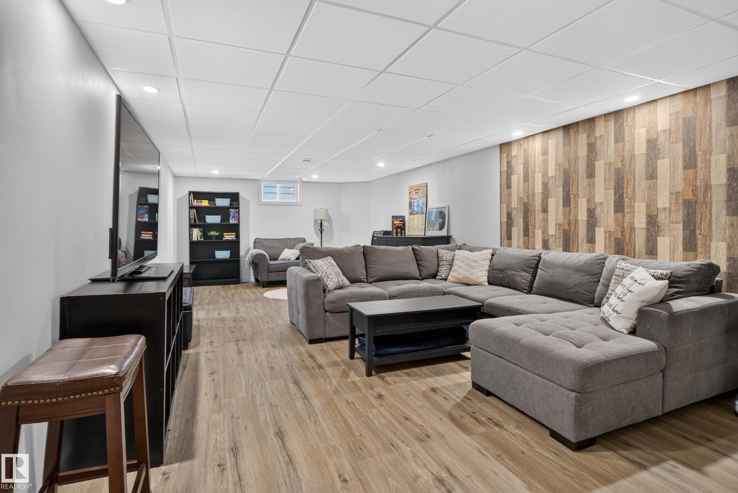 Wood-finish flooring, recessed lighting, drop ceiling, and an accent wall with varying wood tones - 14611 109 Avenue Nw, Edmonton, AB