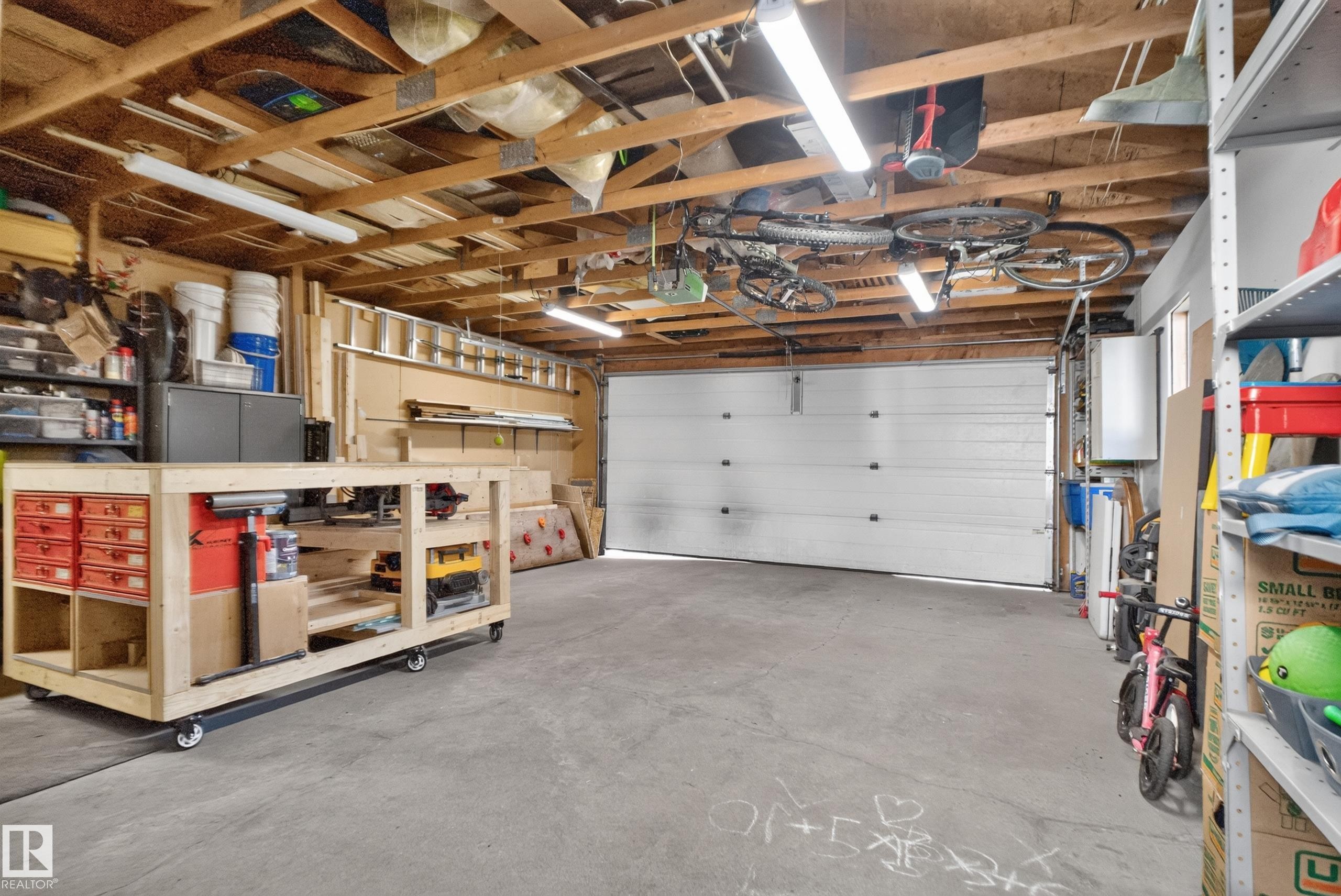 Concrete flooring with exposed wood ceiling beams and fluorescent lighting - 14611 109 Avenue Nw, Edmonton, AB