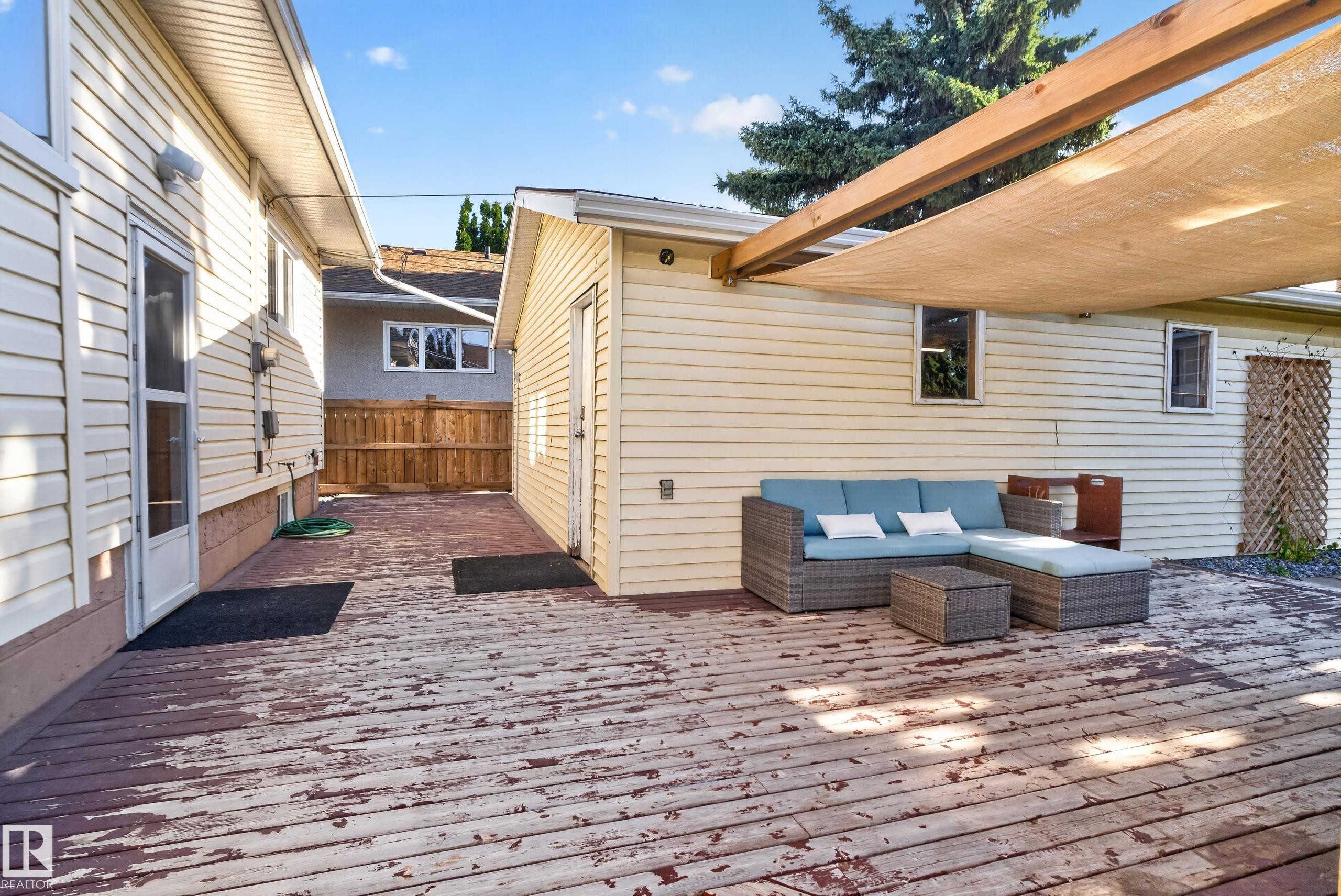 Expansive wood deck with a partial shade covering and privacy fencing - 14611 109 Avenue Nw, Edmonton, AB