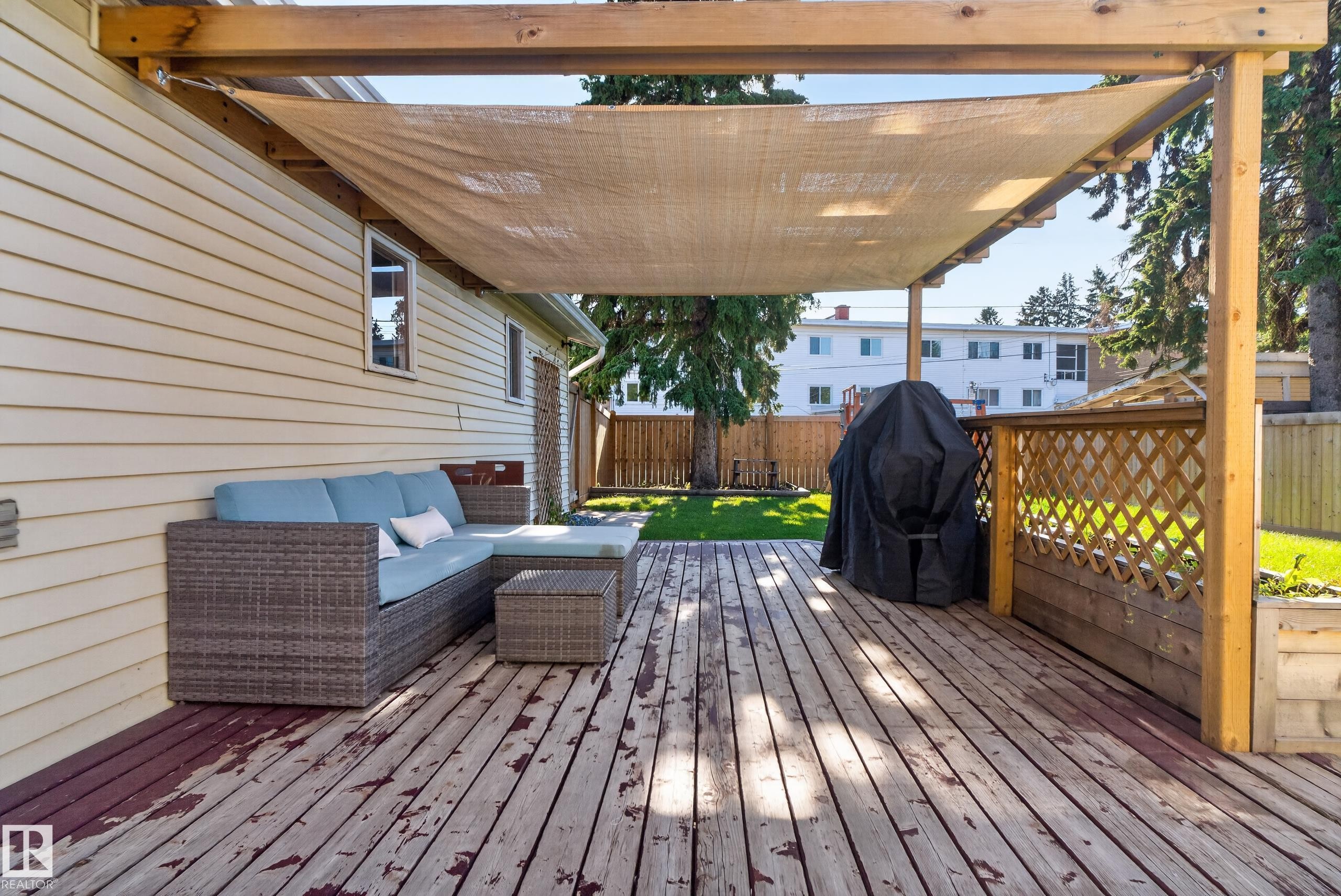 Covered wood deck with sunshade, lattice privacy screen, and light-colored siding - 14611 109 Avenue Nw, Edmonton, AB