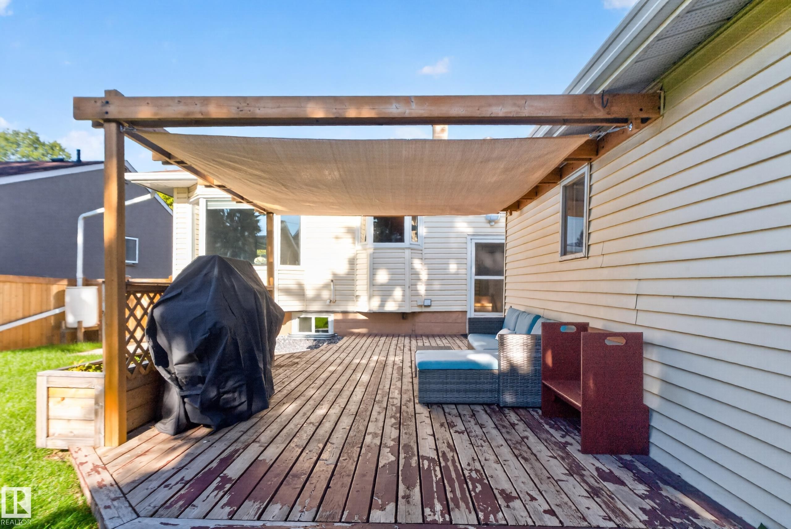 Expansive wood deck with a partial shade awning, lattice privacy screen, and exterior wall with horizontal siding - 14611 109 Avenue Nw, Edmonton, AB