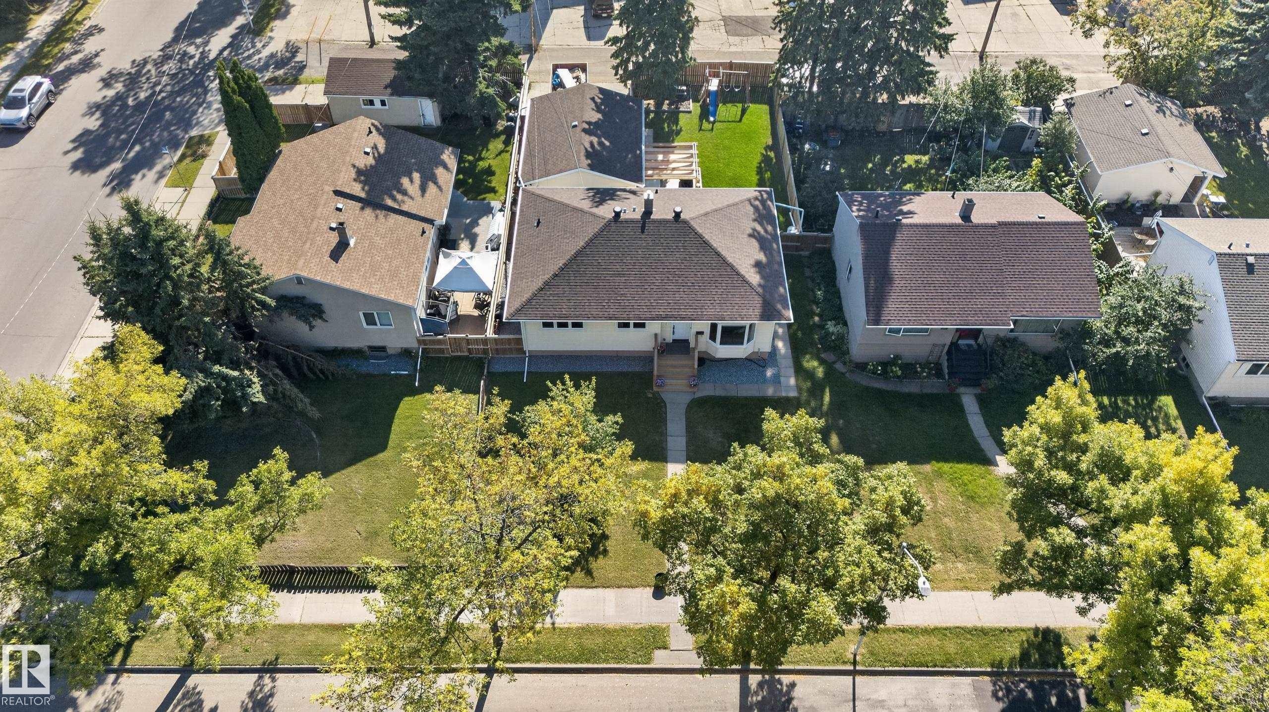 Front-facing property with a sidewalk, mature trees, and a shingled roof - 14611 109 Avenue Nw, Edmonton, AB