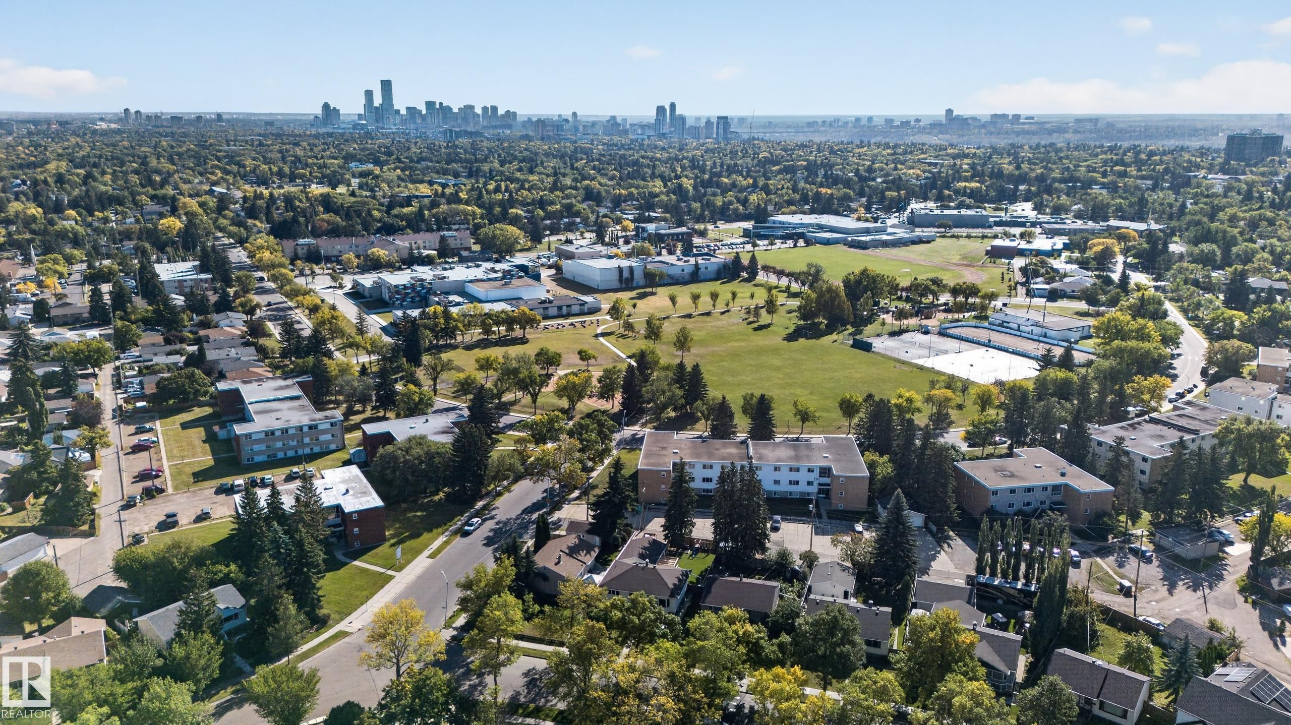 Expansive neighborhood featuring mature trees, paved streets, and a distant city skyline - 14611 109 Avenue Nw, Edmonton, AB