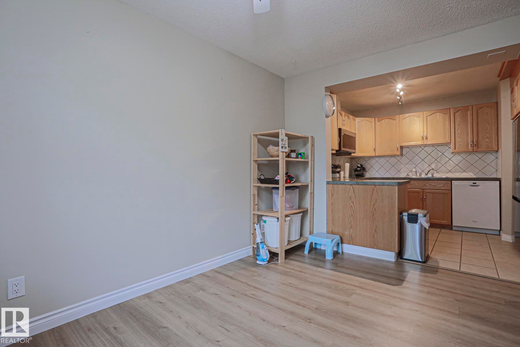 Open kitchen featuring wood cabinetry, integrated microwave, tile backsplash, and a dishwasher - 319 Telford Court, Leduc, AB