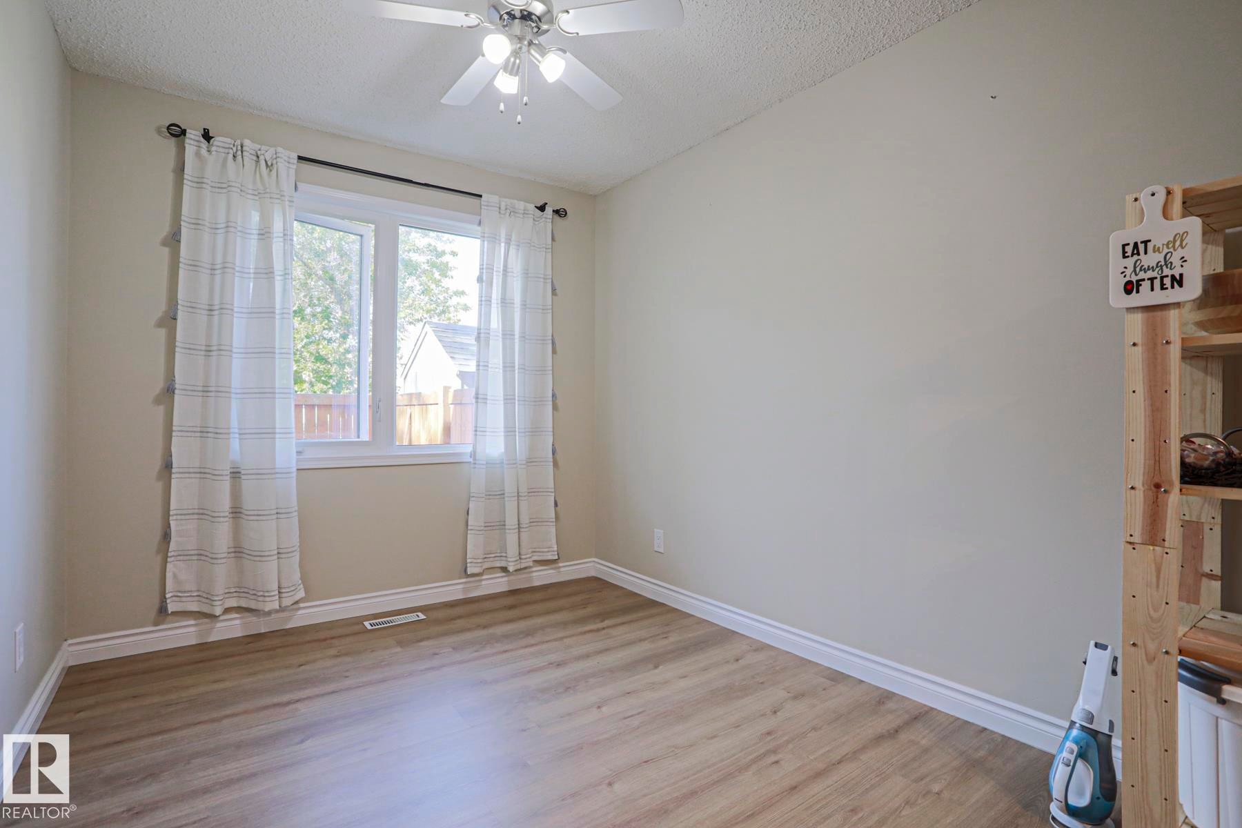 Wood-finish flooring, white trim, and a ceiling fan with integrated lighting - 319 Telford Court, Leduc, AB