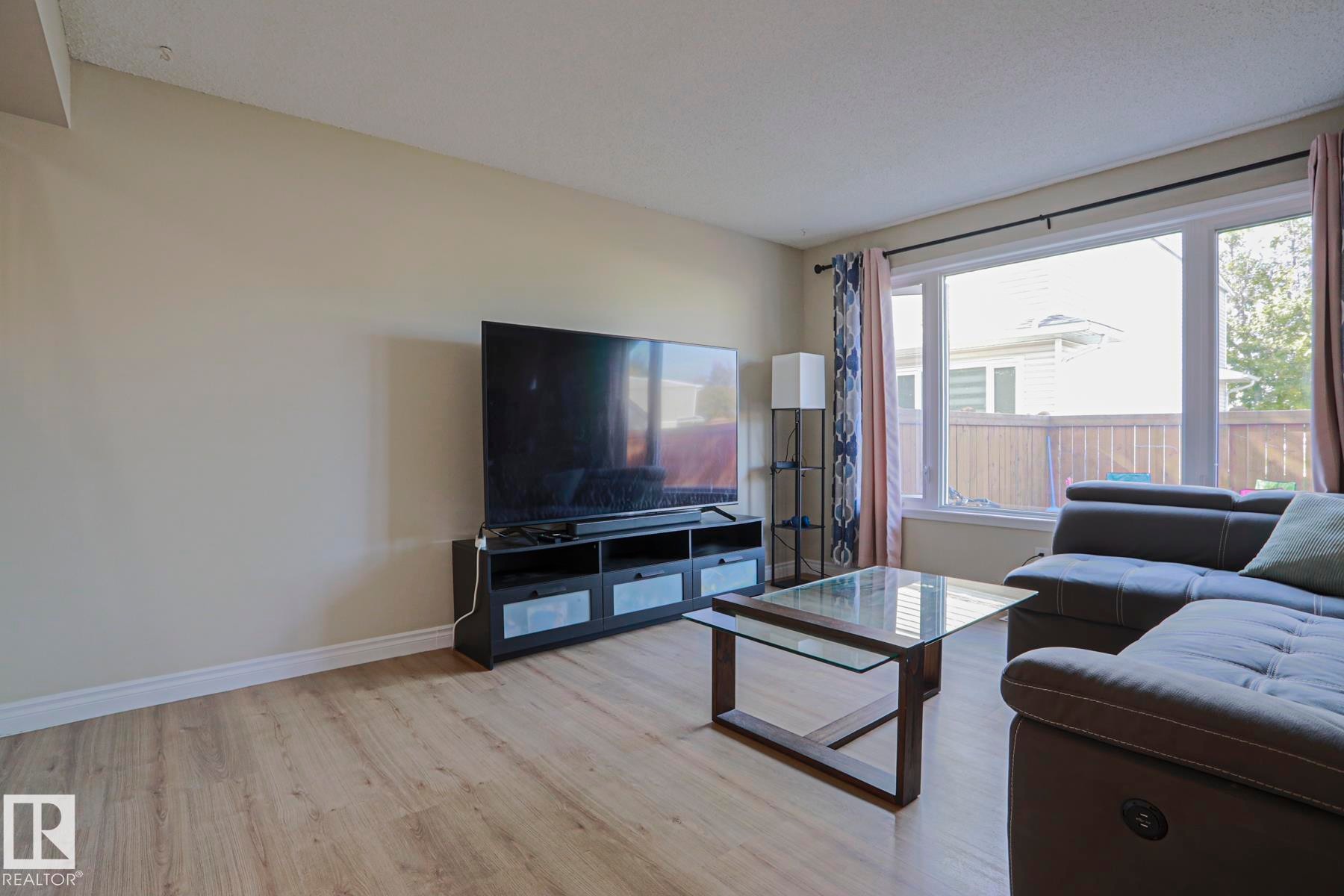 Wood-finish flooring, neutral wall paint, and large picture windows - 319 Telford Court, Leduc, AB