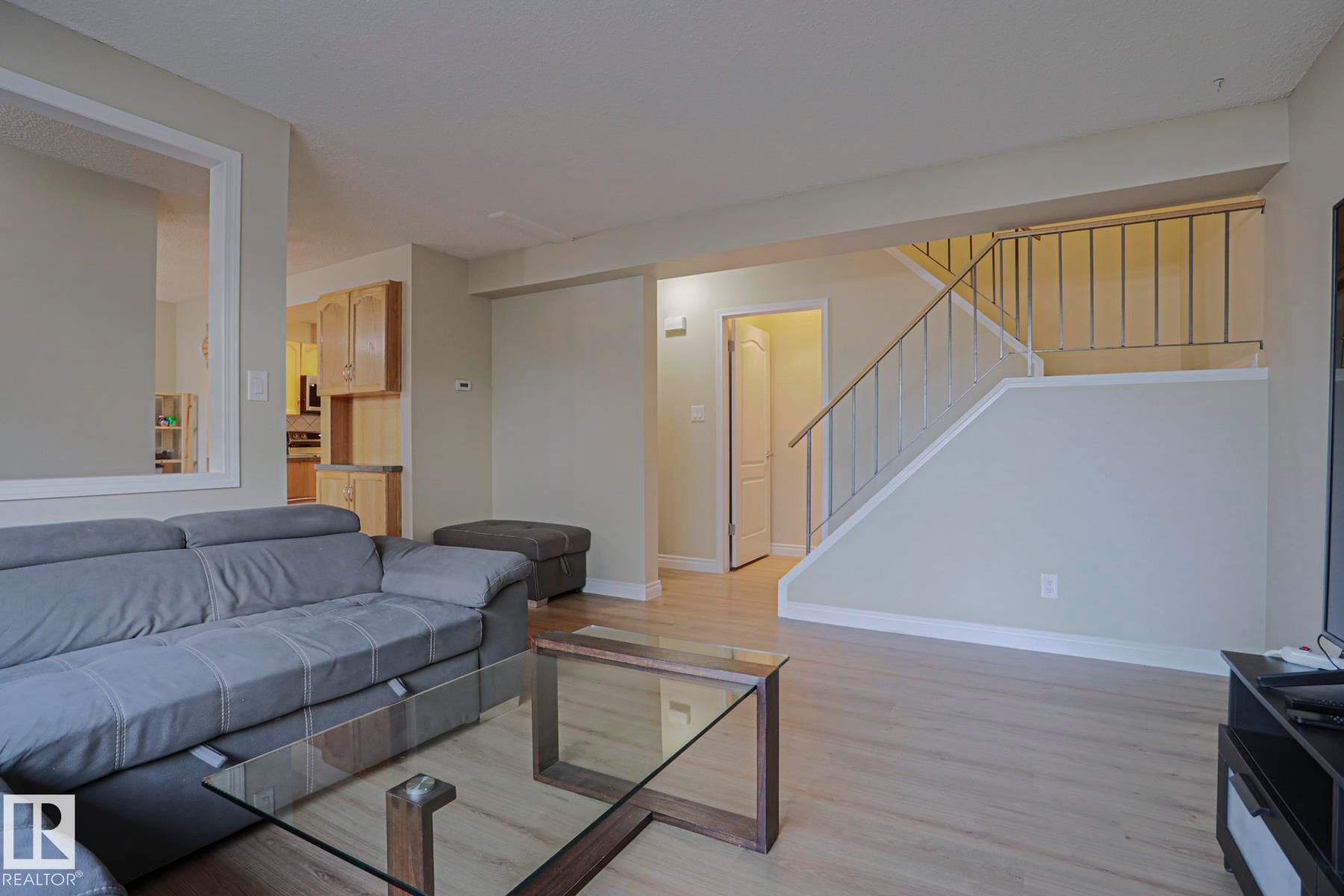 Wood-finish flooring throughout, light-toned walls, and a staircase with metal railings - 319 Telford Court, Leduc, AB