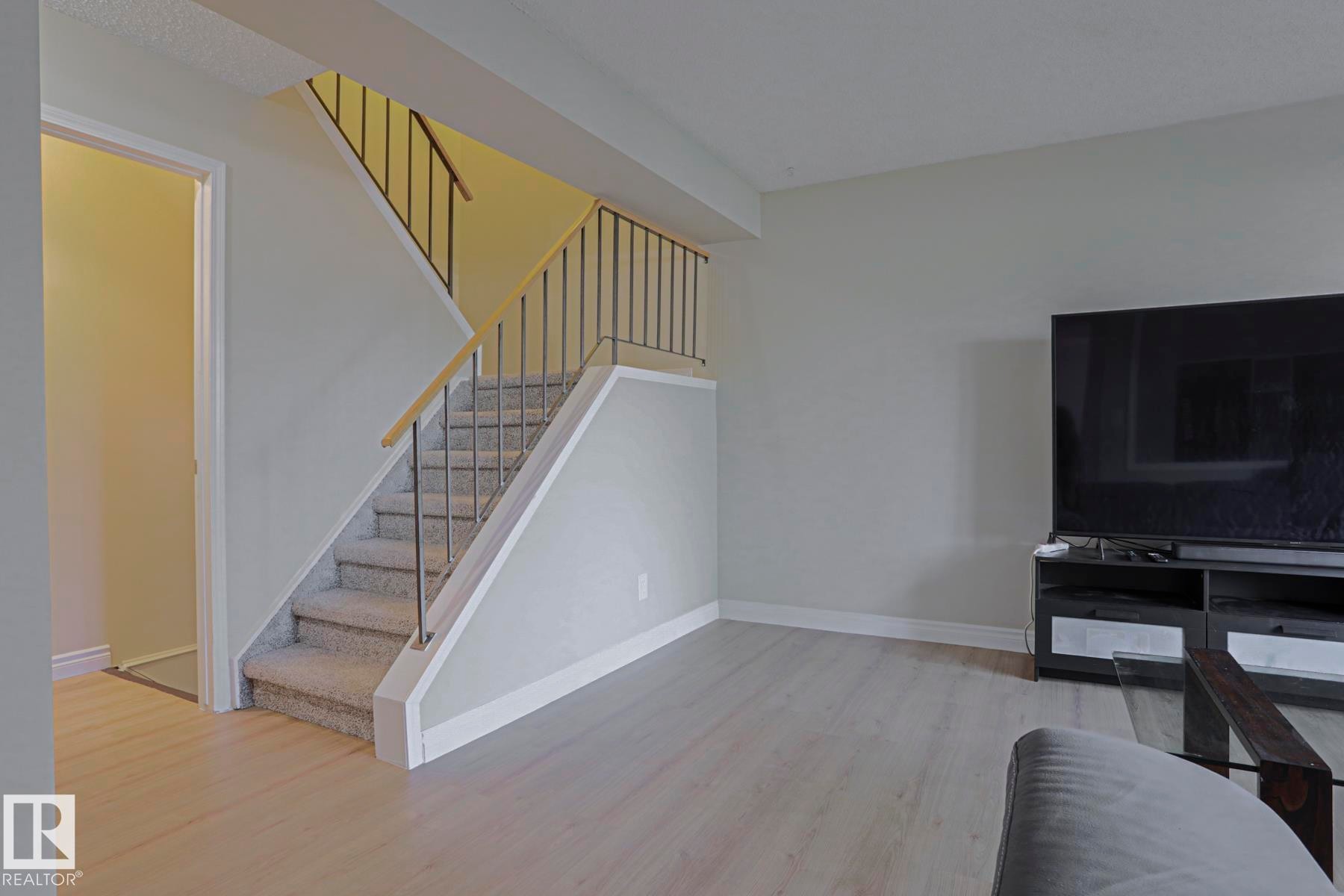 Carpeted staircase with metal balusters and a wood-finish handrail - 319 Telford Court, Leduc, AB