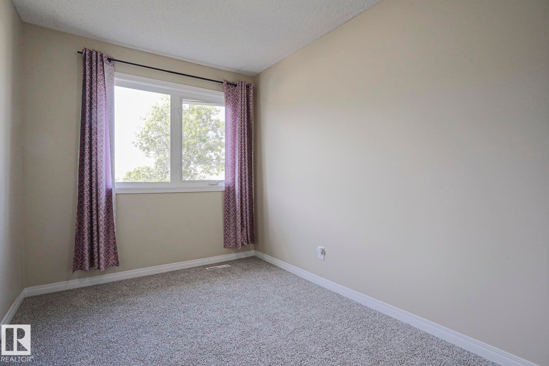 Wall-to-wall carpeting, neutral wall color, and a window with white trim - 319 Telford Court, Leduc, AB
