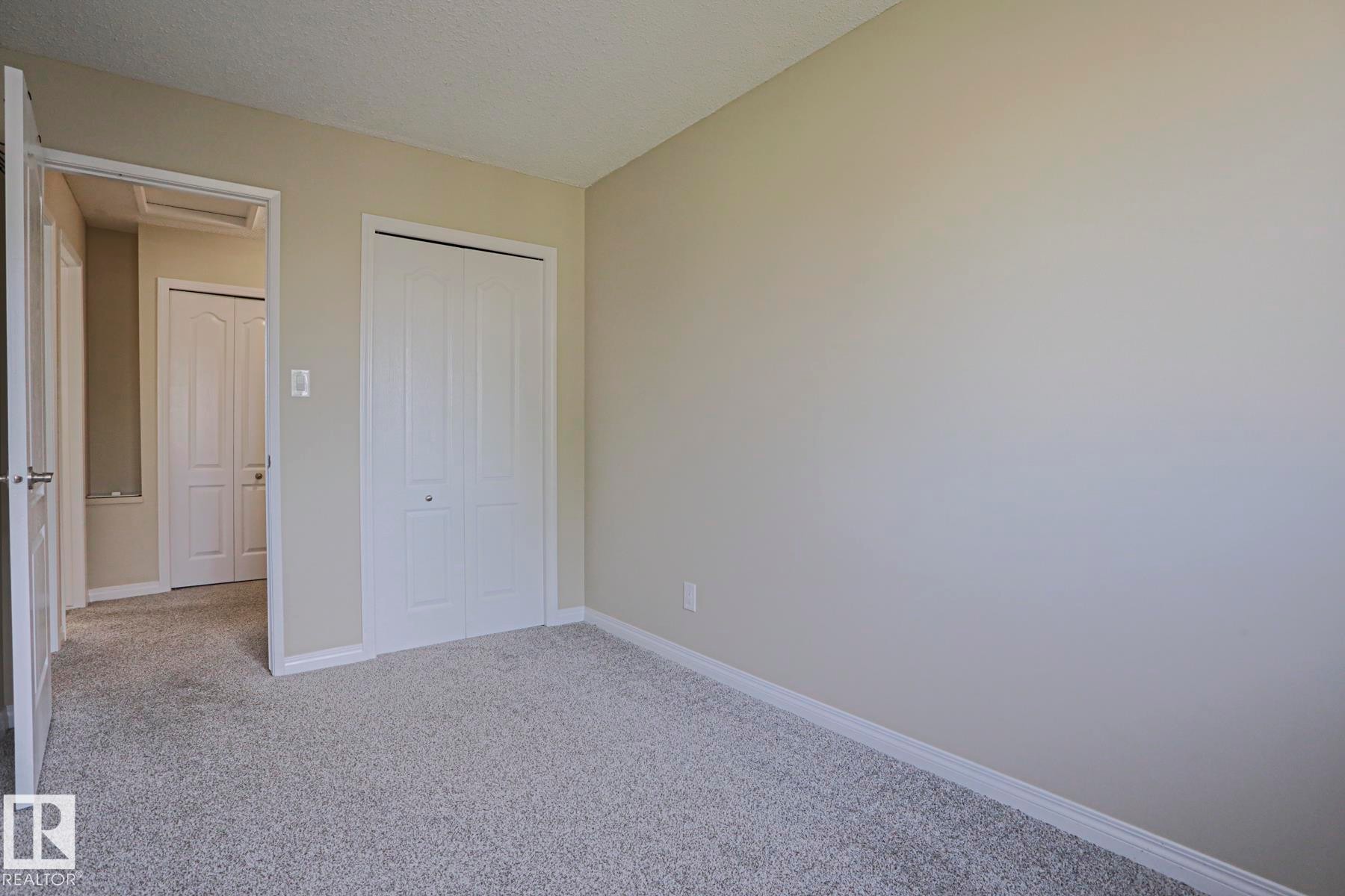 Neutral-toned walls, light-colored carpeting, white baseboards, and white bi-fold closet doors - 319 Telford Court, Leduc, AB