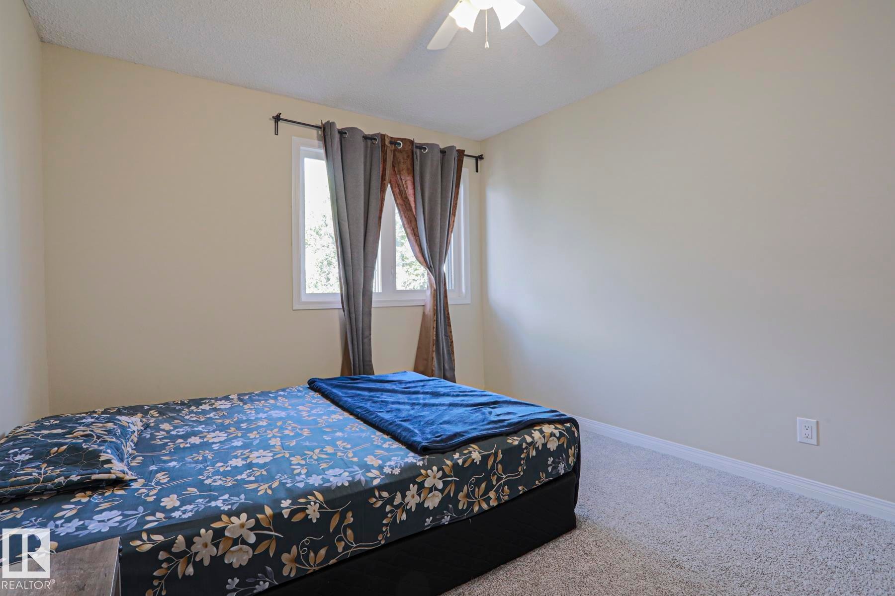 Neutral-toned walls, light-colored carpet, a ceiling fan, and a window with white trim - 319 Telford Court, Leduc, AB